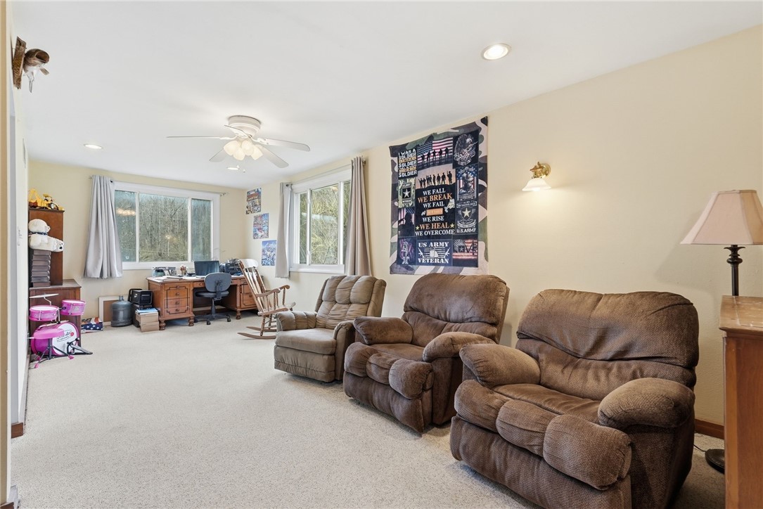 Recreation room with brown recliners, a desk by the windows, a rocking chair, and a small drum set.
