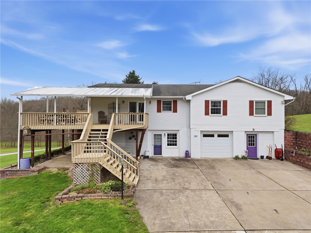 White two-story home with a covered raised deck, red shutters, attached garage, and wide concrete driveway.