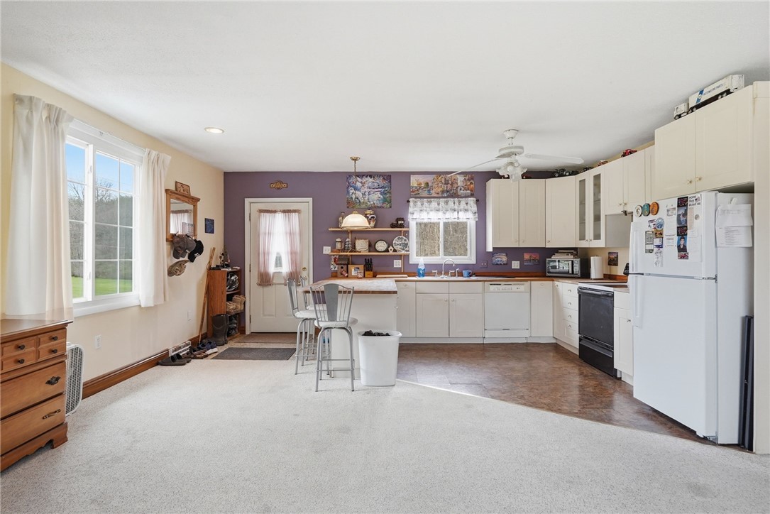 Kitchen with white cabinets and appliances, a bar-height peninsula, and purple accent wall.