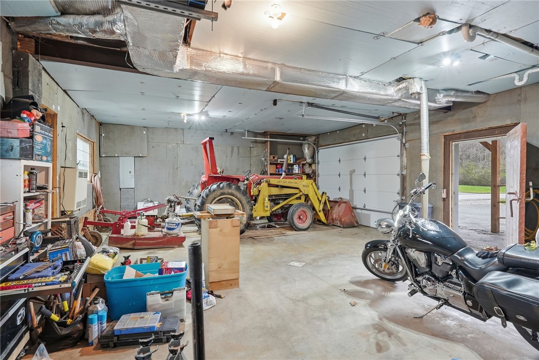Garage with a yellow tractor, black motorcycle, and shelves of tools and storage.