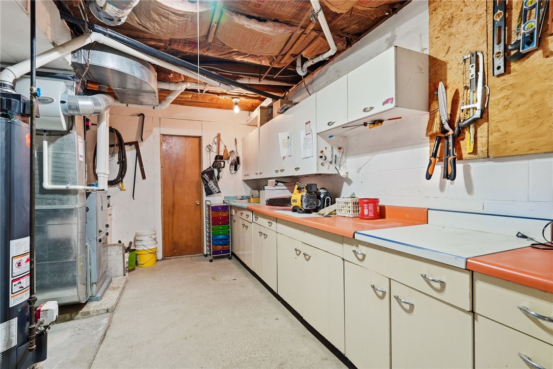 Basement utility room with long work counters, storage cabinets, and exposed HVAC equipment.