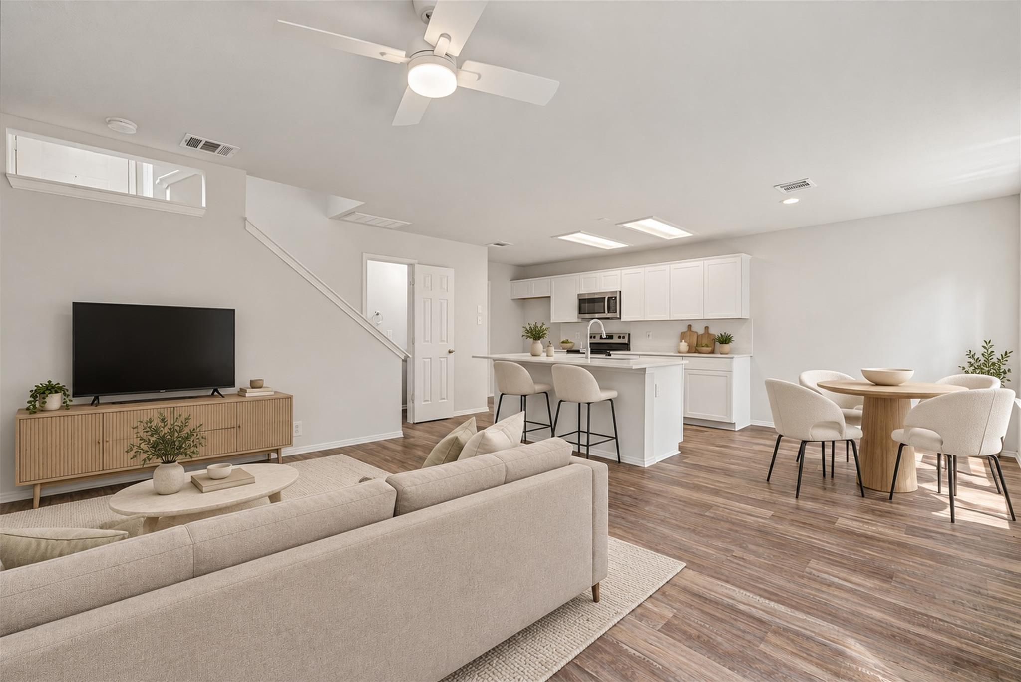 Open living area with a beige sofa, white kitchen island, and round dining table.