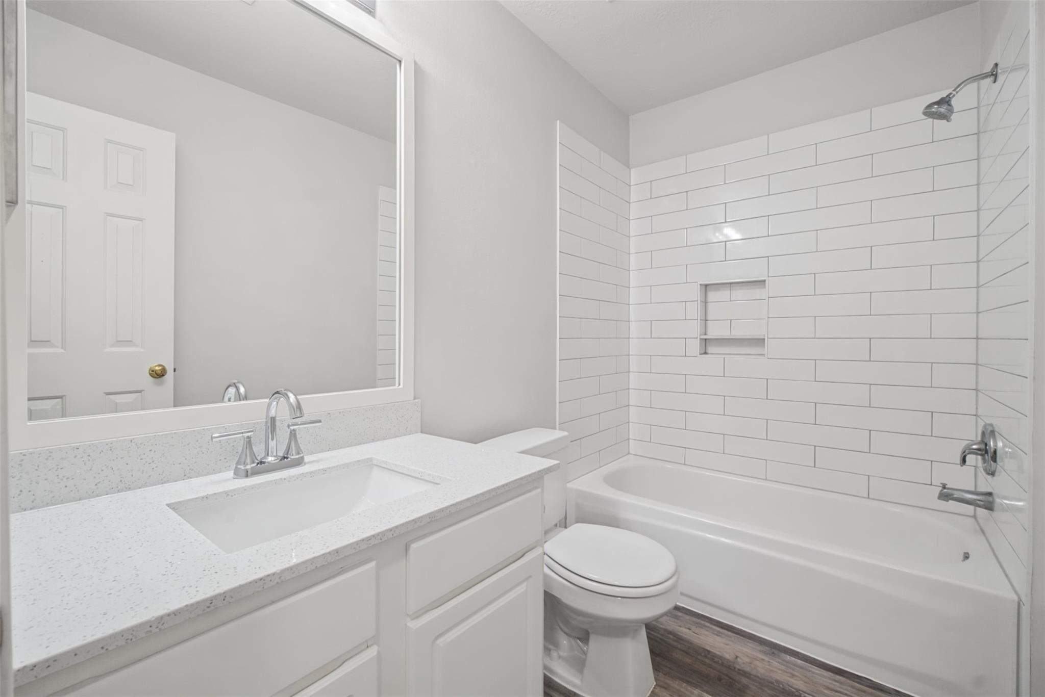 Bathroom with a white vanity and a bathtub surrounded by white subway tile.