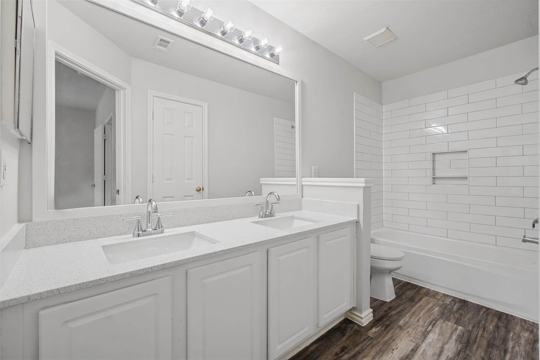 Bathroom with a double-sink vanity and white subway-tile tub surround.