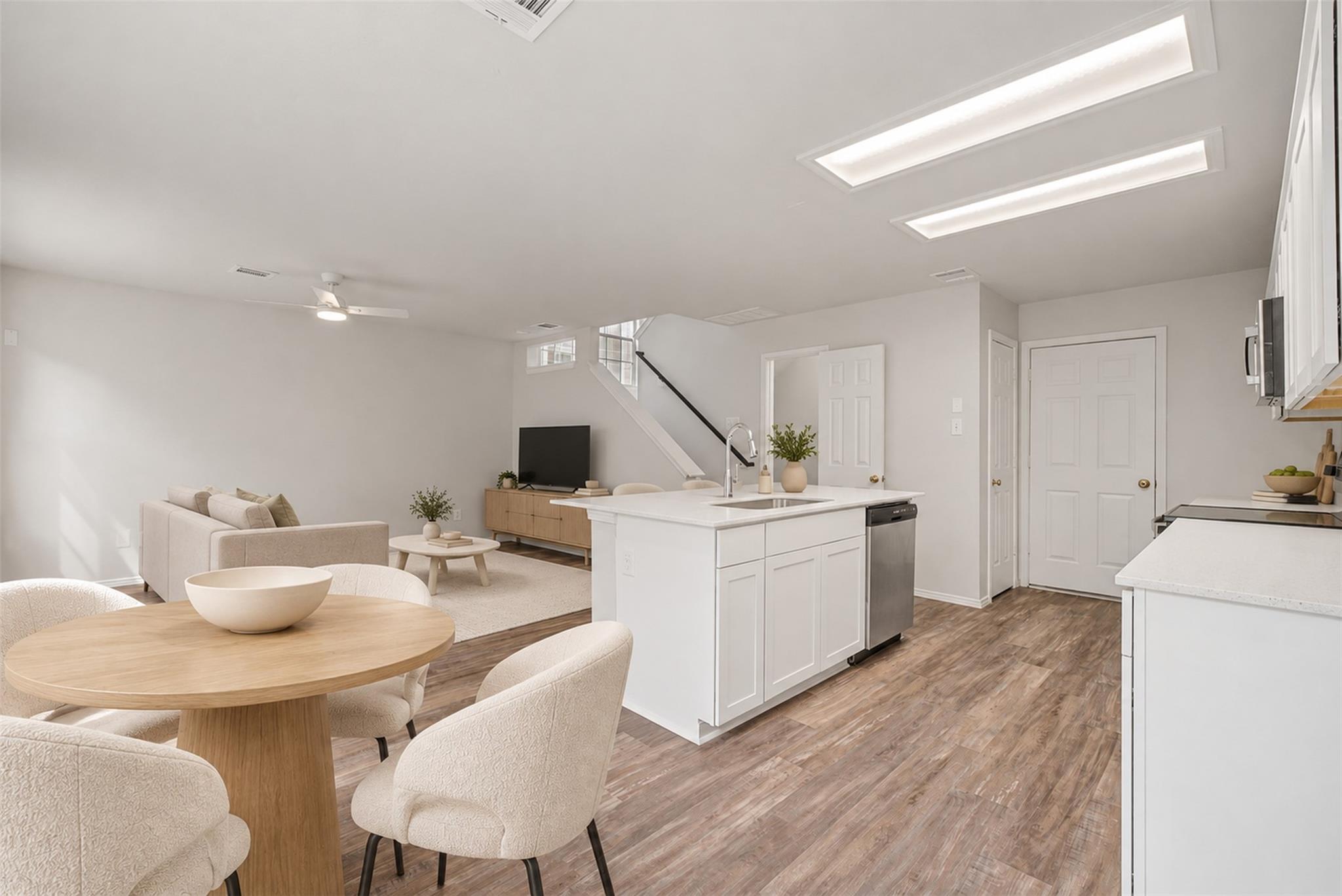 Open-plan kitchen and dining area with a white island, round wood table, and staircase.