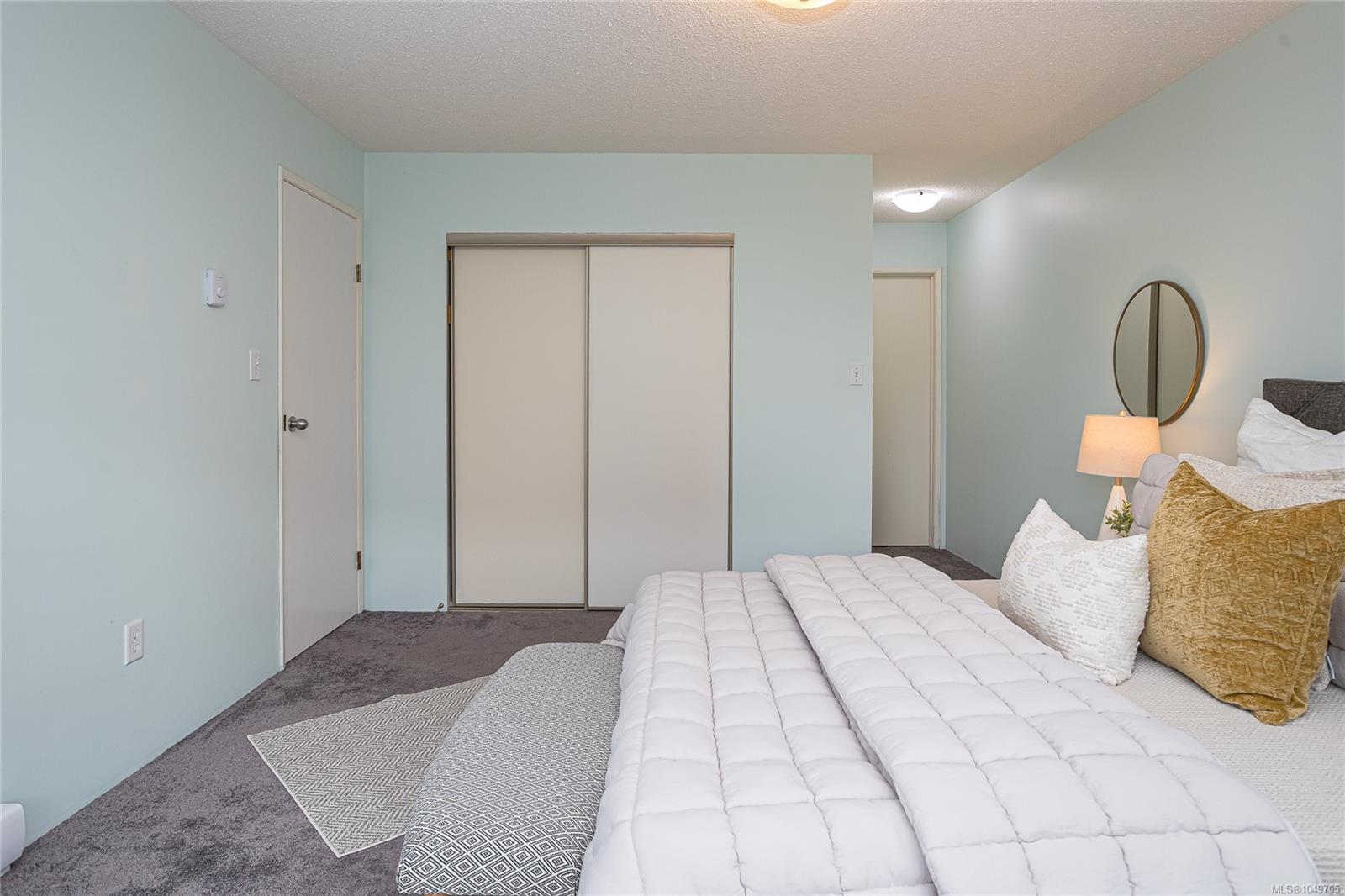 Furnished bedroom with a white quilted bed, sliding closet doors, and pale blue walls.