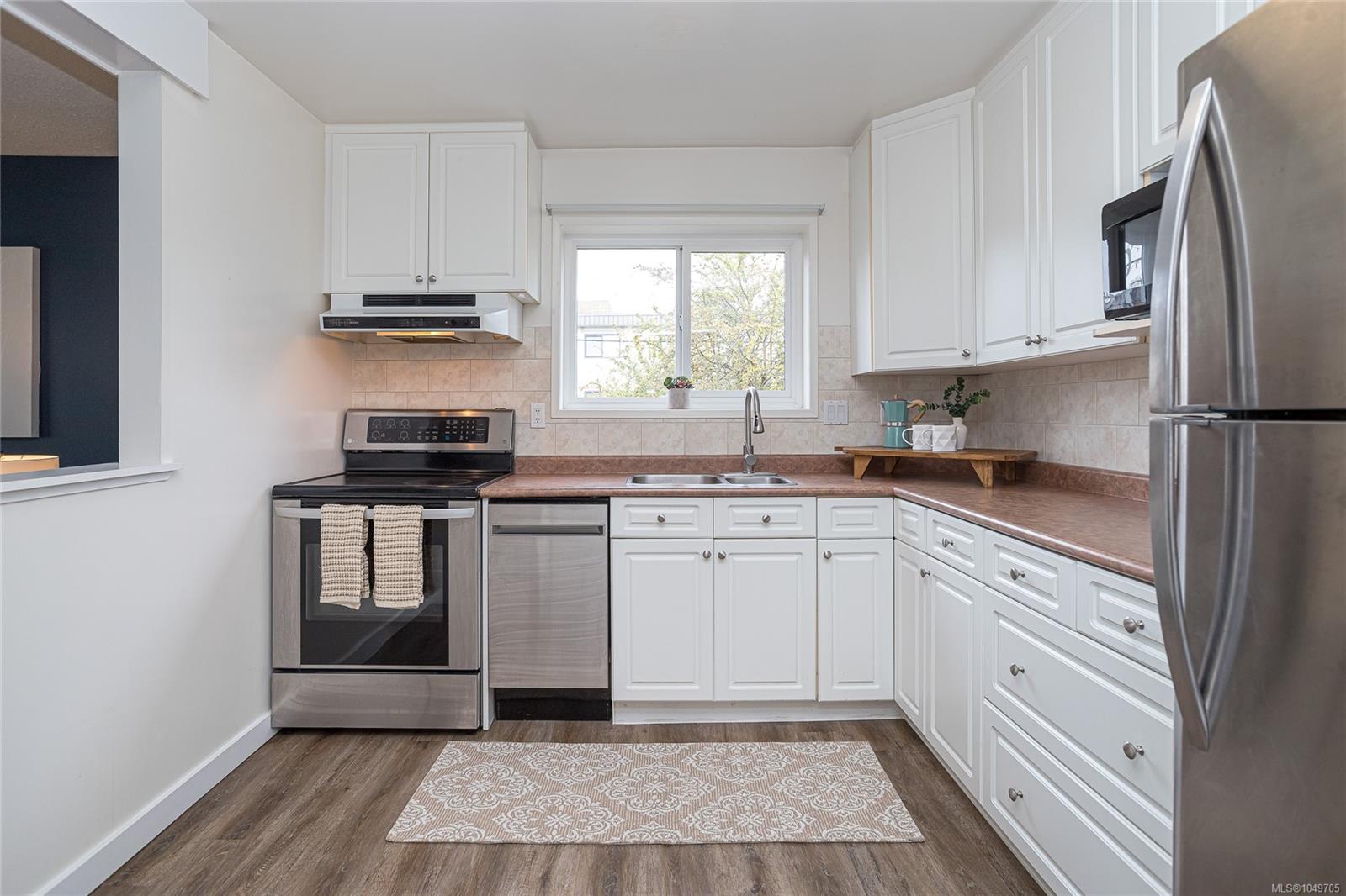 Kitchen with white cabinets, stainless steel appliances, and a sink beneath the window.