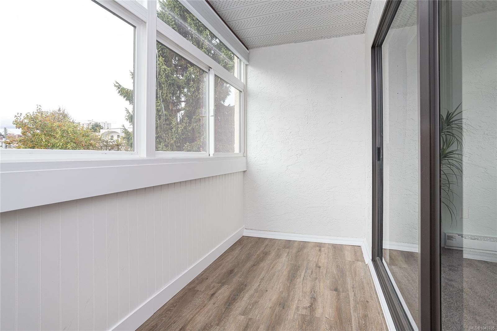 Enclosed sunroom with wood-look flooring, large windows, and sliding glass doors.