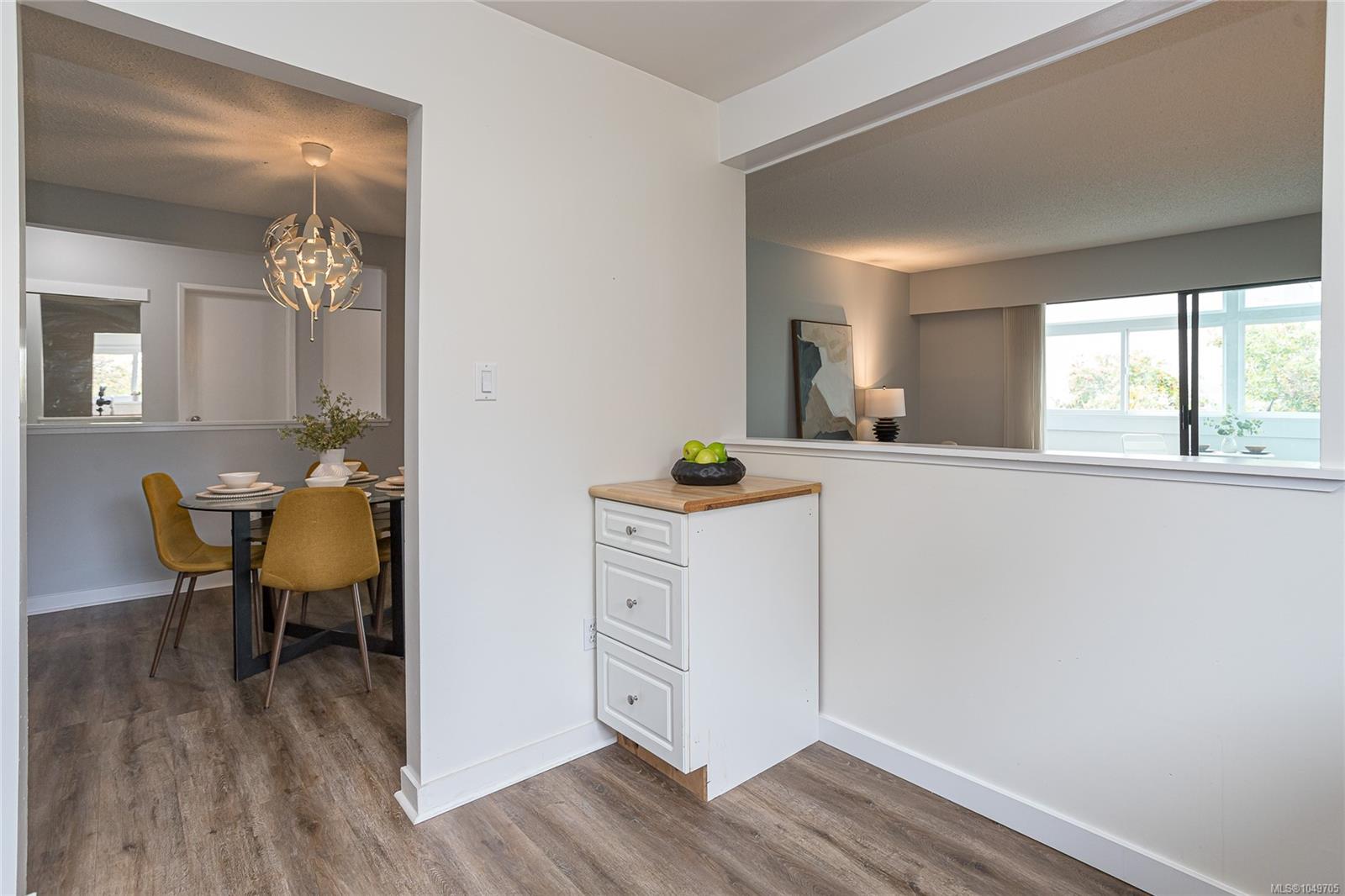 Condo dining area with mustard chairs and pendant light, adjoining a bright living room.