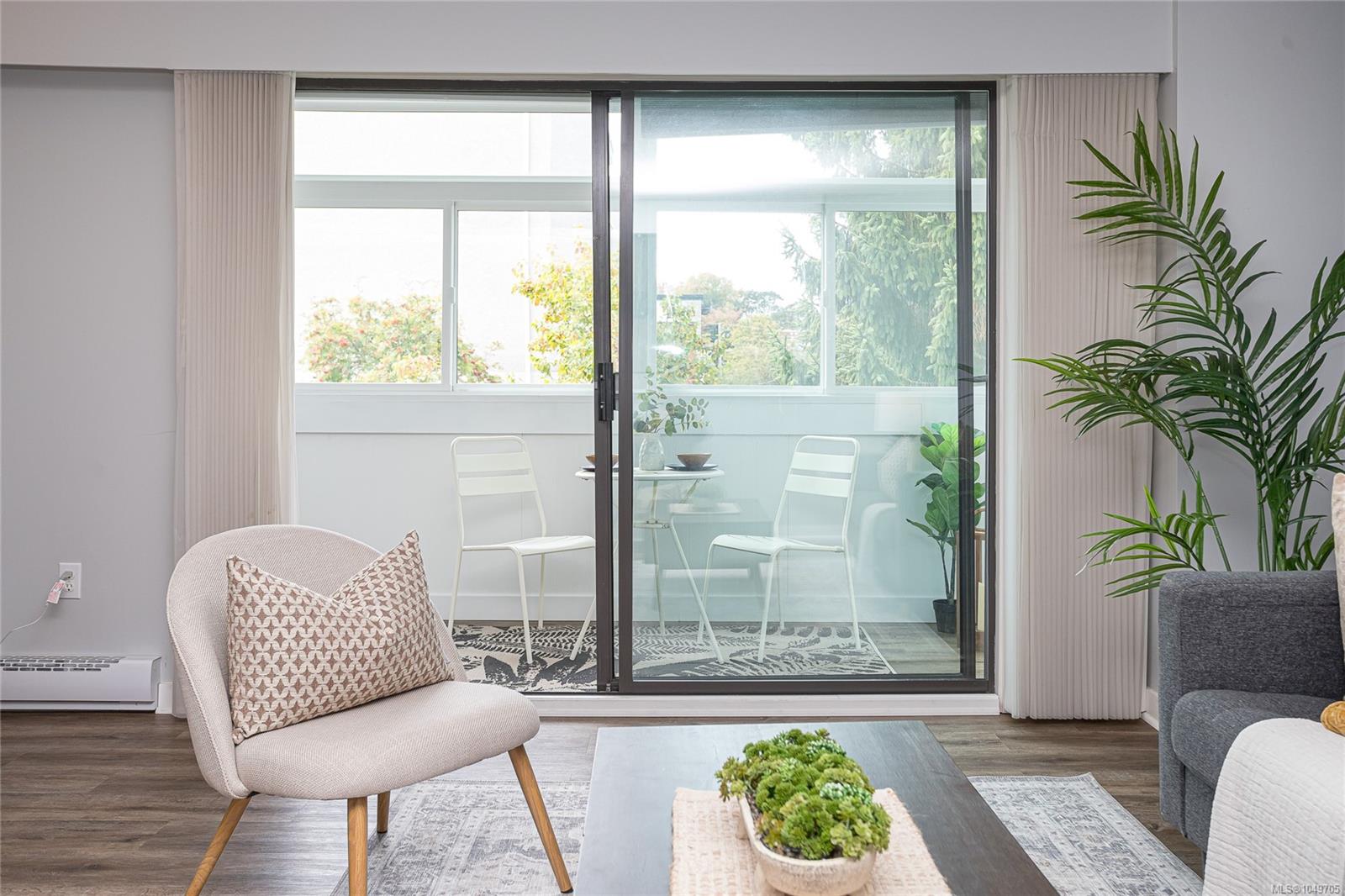 Staged living room with sliding doors opening to a bright enclosed balcony.