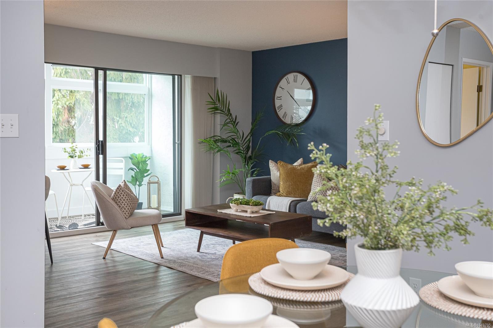 Staged living room with a blue accent wall, large windows, and sliding doors to a balcony.