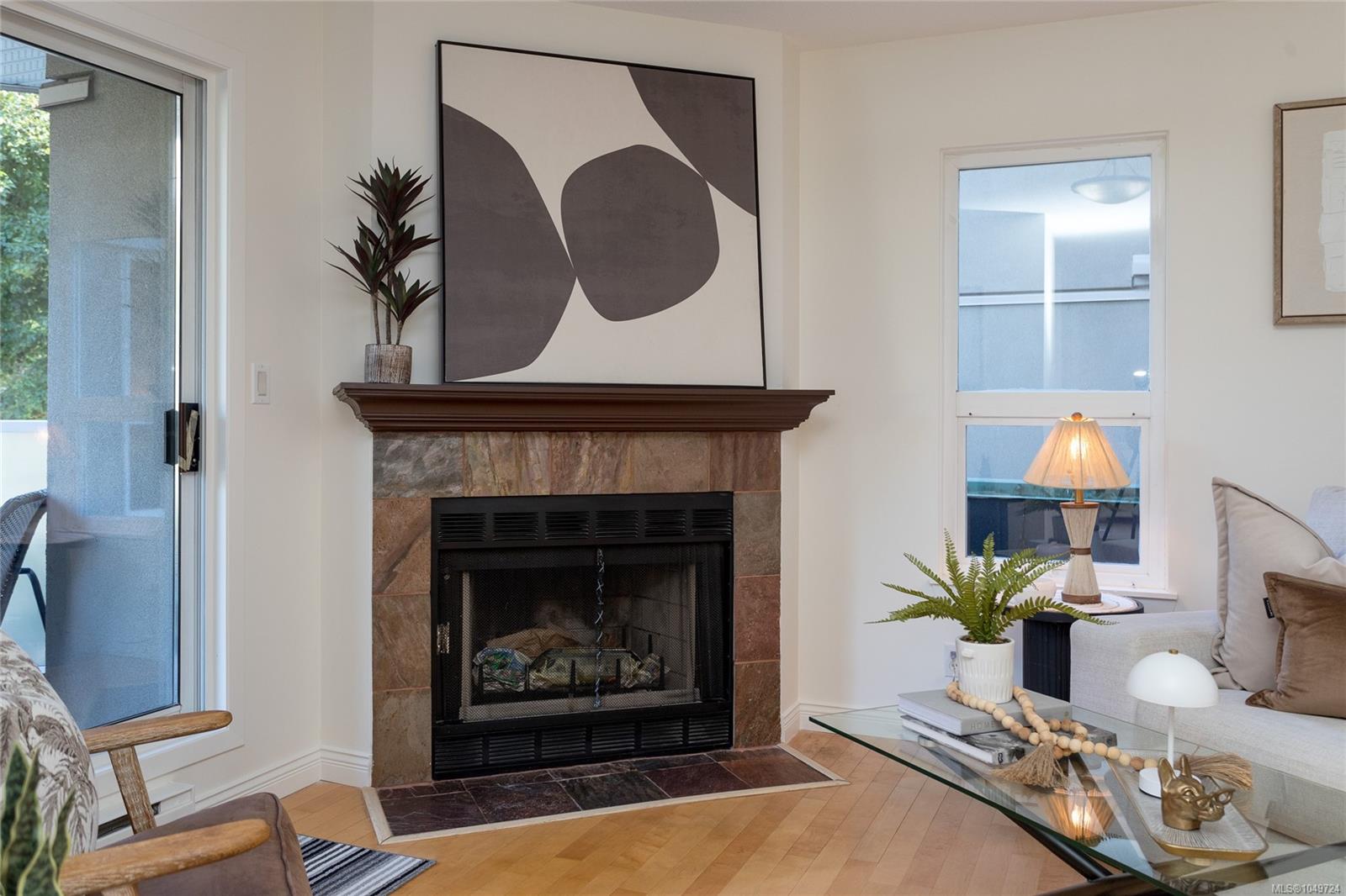 Living room with a stone fireplace, hardwood floors, and a sliding glass door to the balcony.