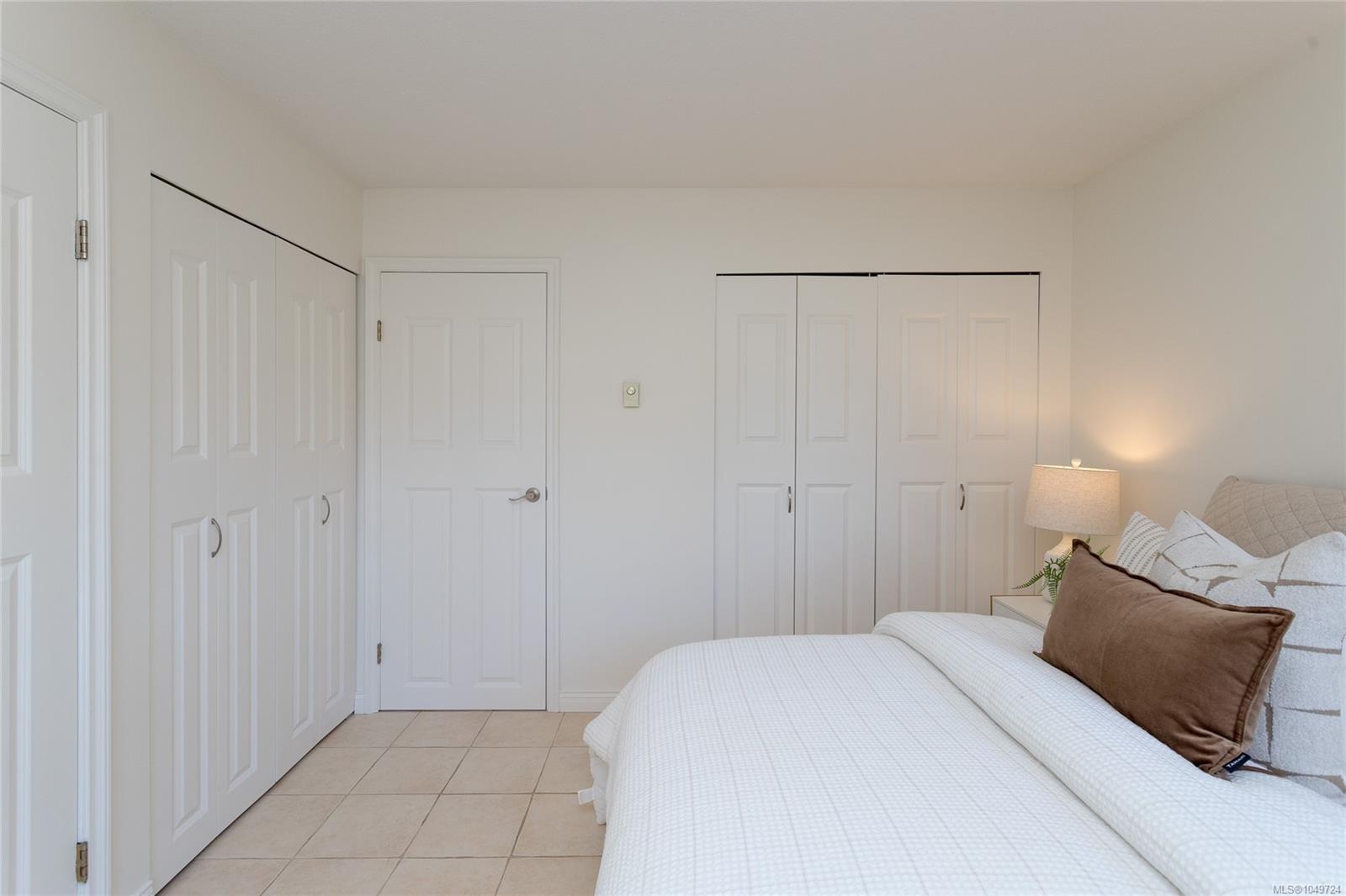 Furnished bedroom with a white bed, brown accent pillow, and white closet doors.