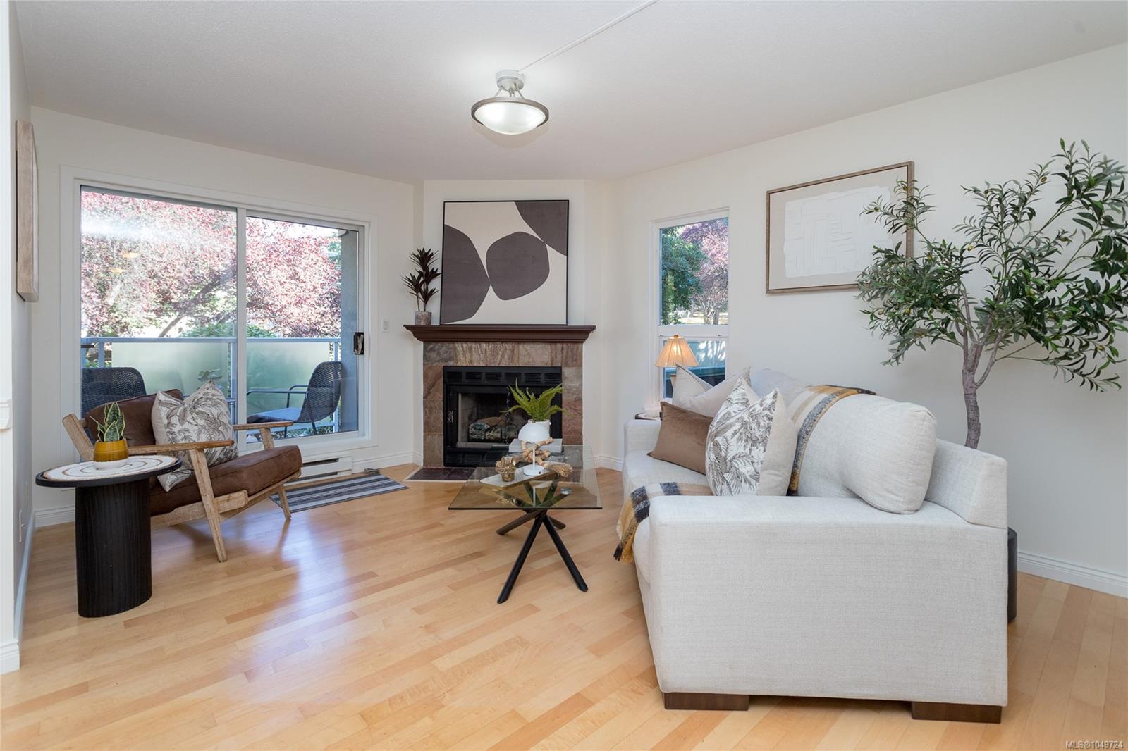 Staged living room with a stone fireplace, cream sofa, and balcony doors.