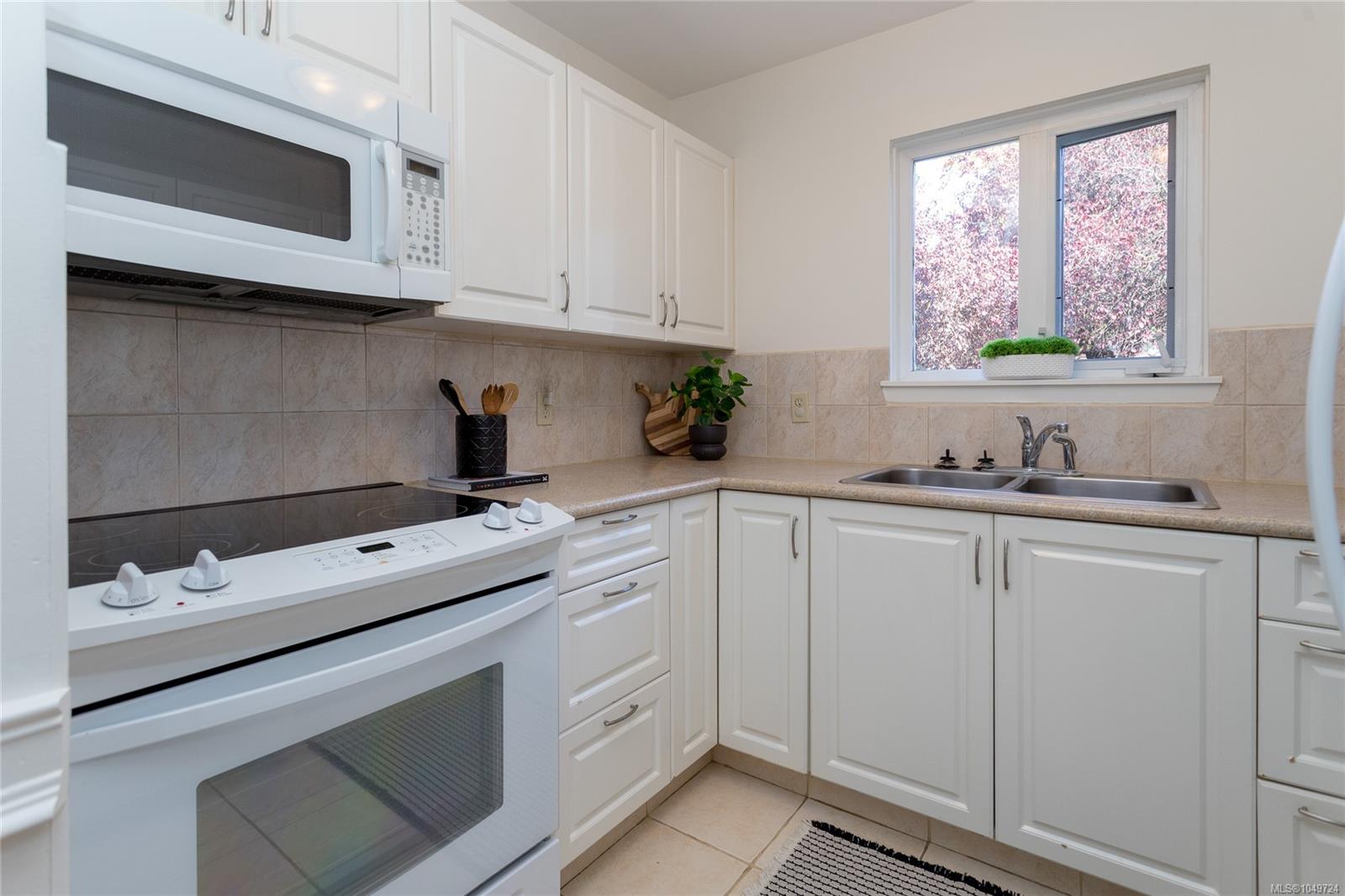 Kitchen with white cabinets, a white range, and a double-basin sink beneath a window.
