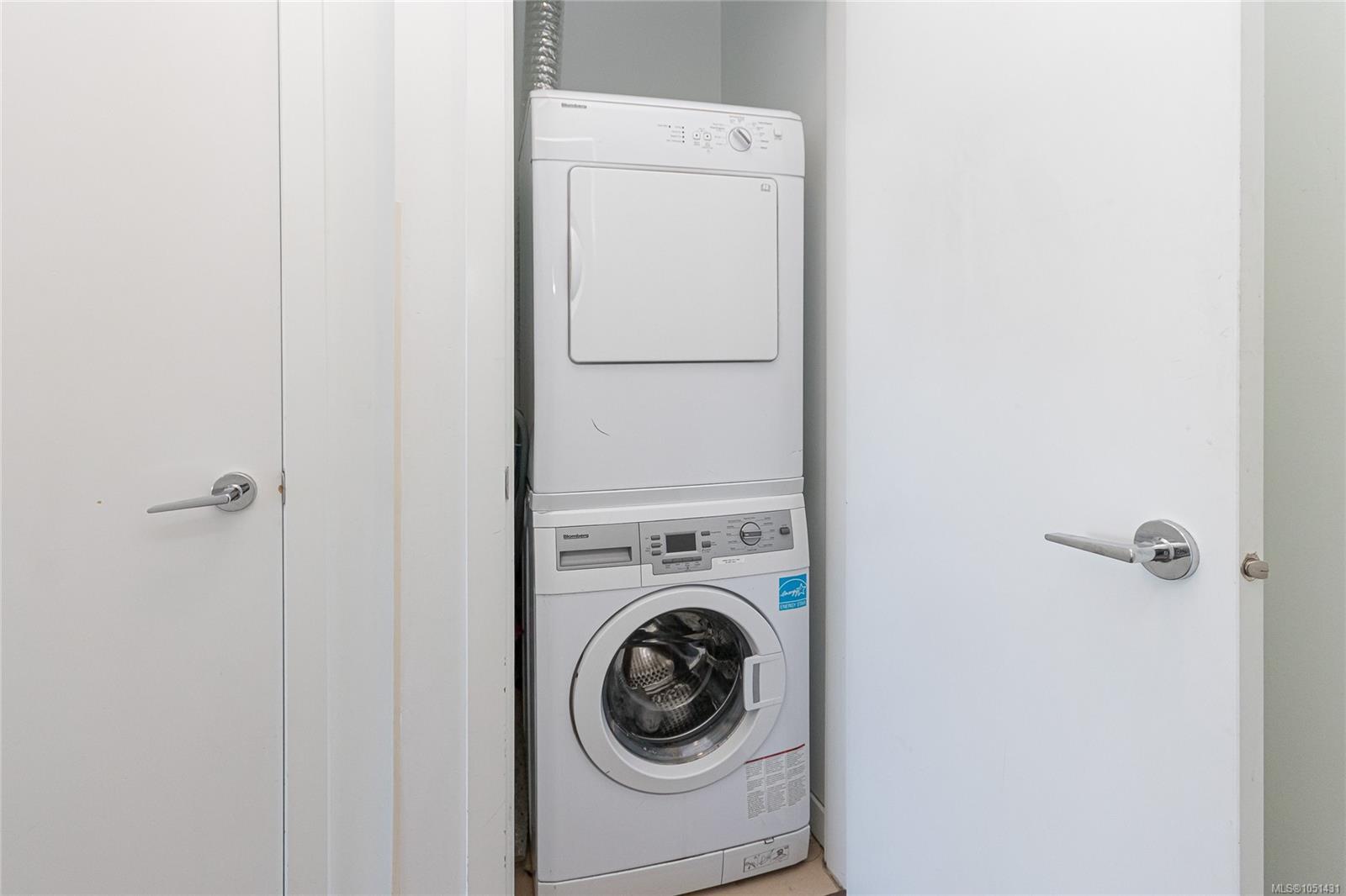 Stacked white washer and dryer in a narrow laundry closet.