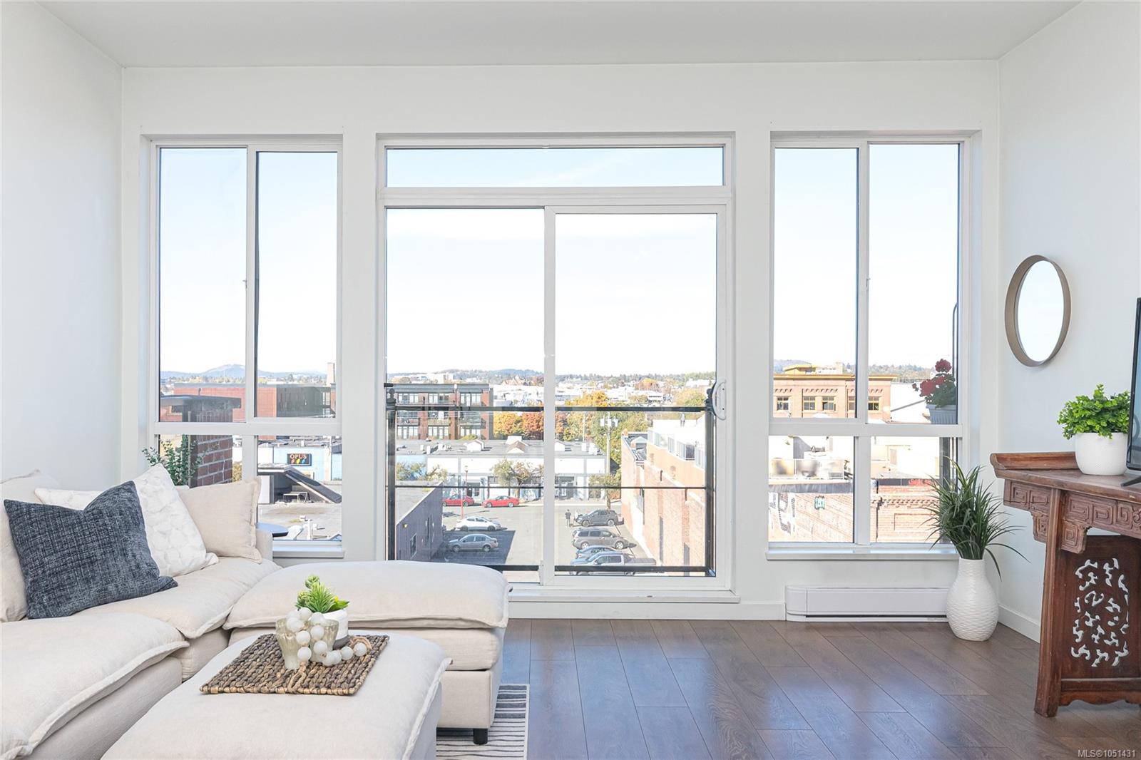 Furnished condo living room with a cream sectional and large windows overlooking downtown.