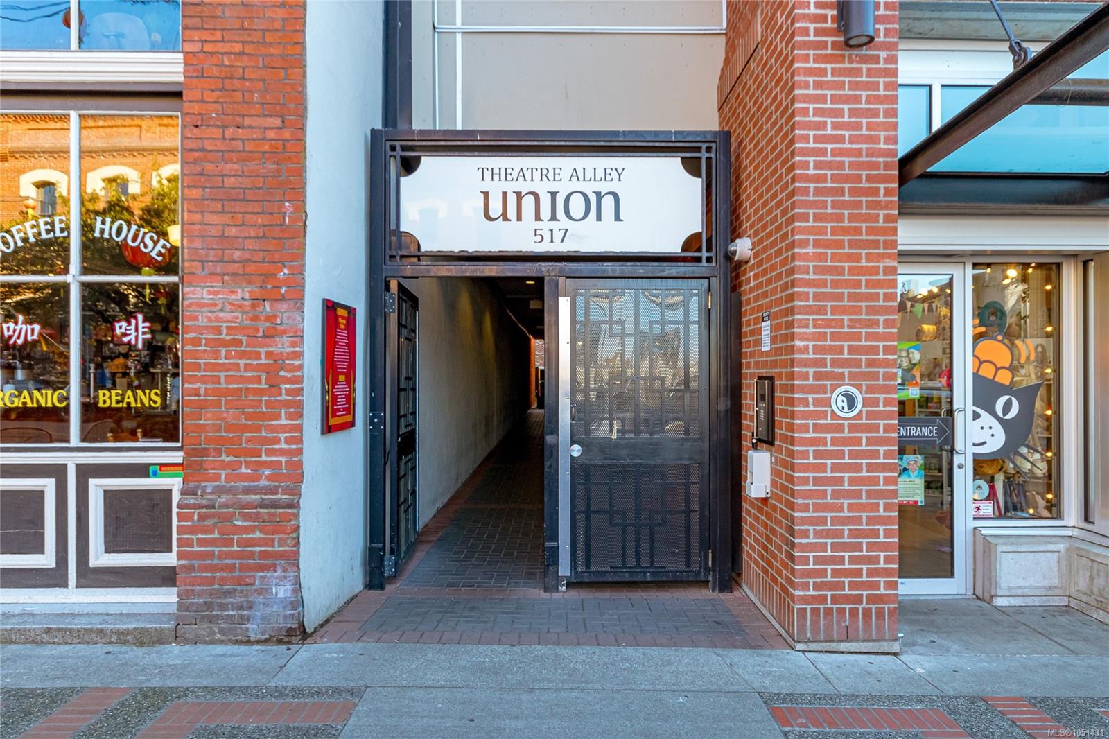 Theatre Alley Union entrance at 517, with a black metal gate framed by red brick walls.