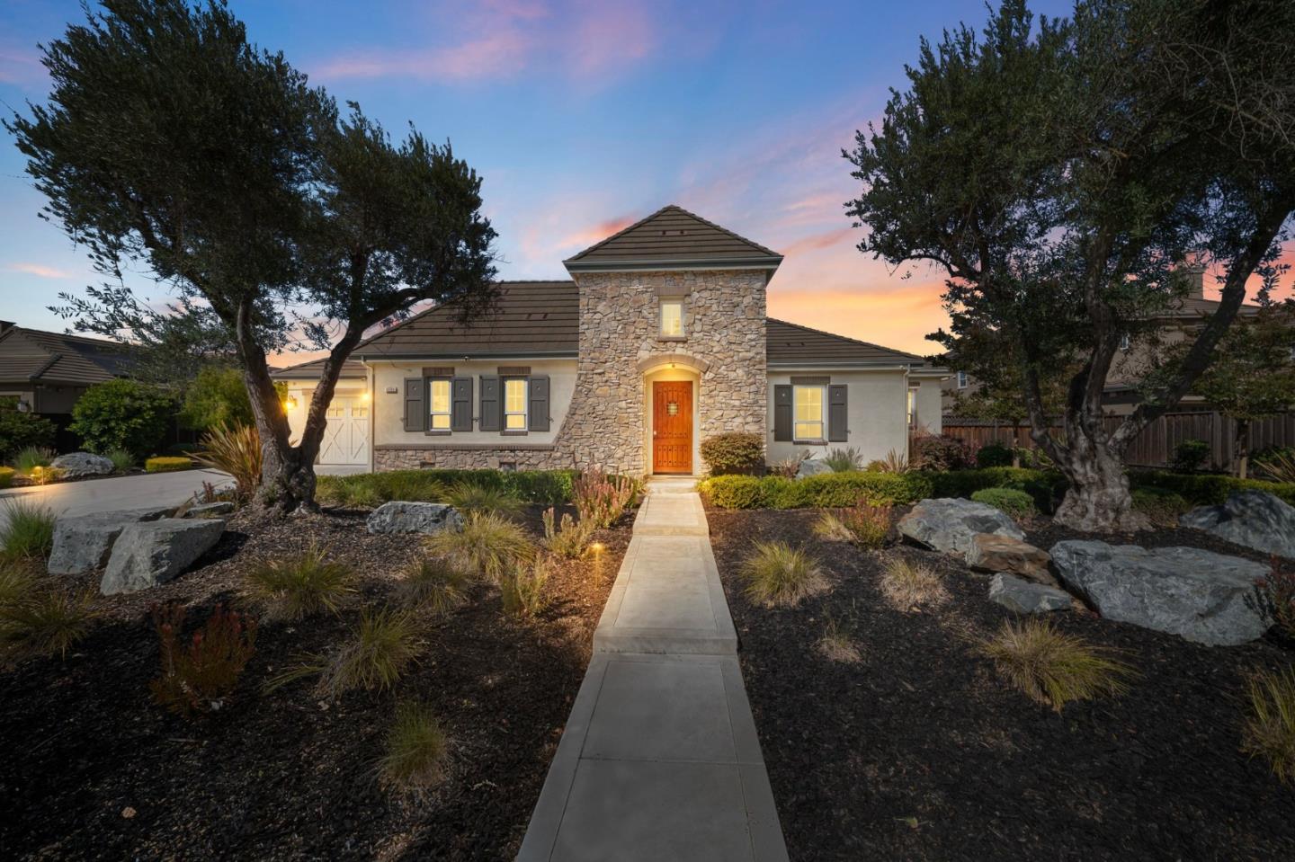 Home with a stone entry tower and landscaped front yard at dusk.