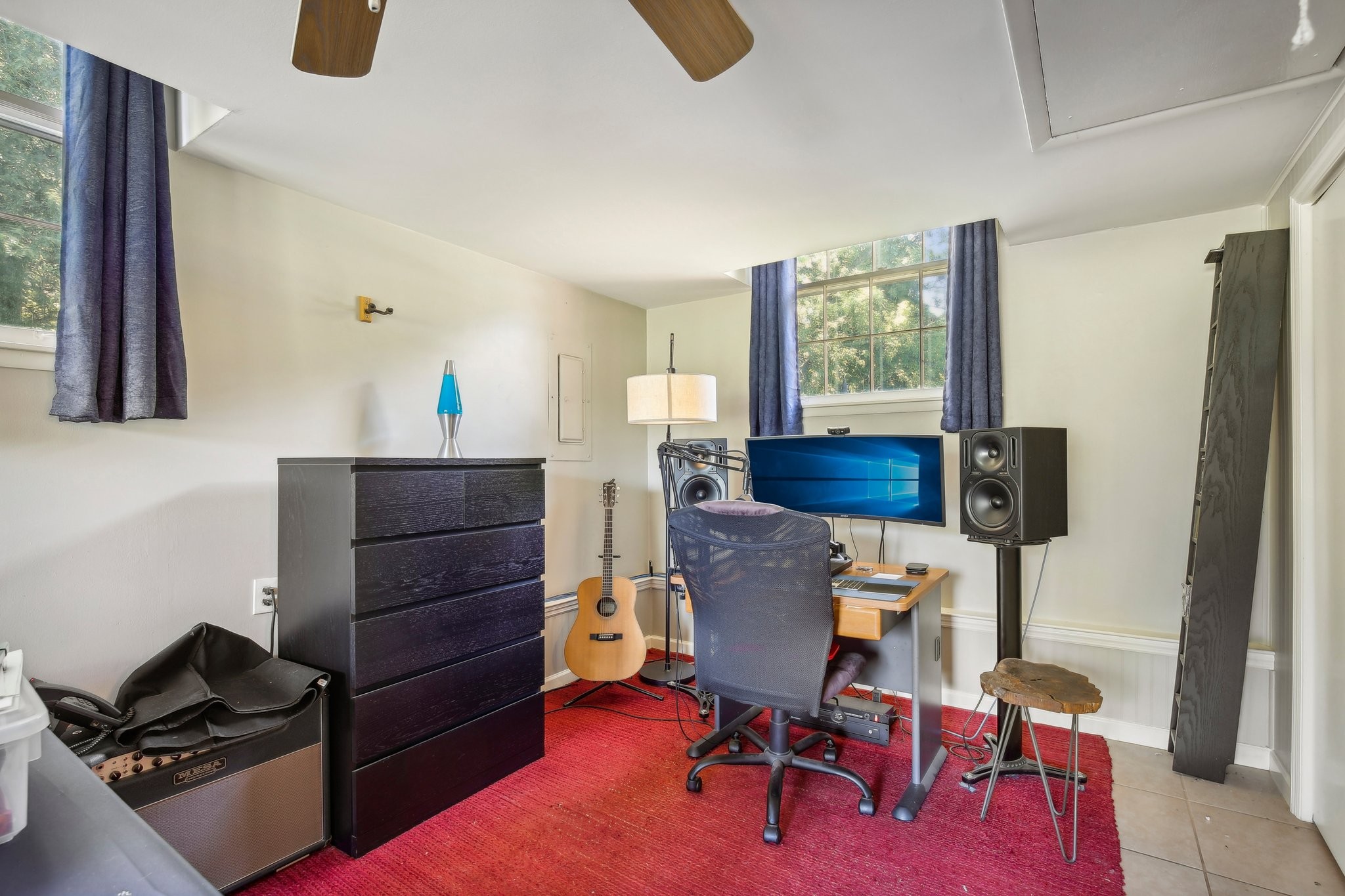 Home office and music workspace with studio speakers, a guitar, and a red rug.