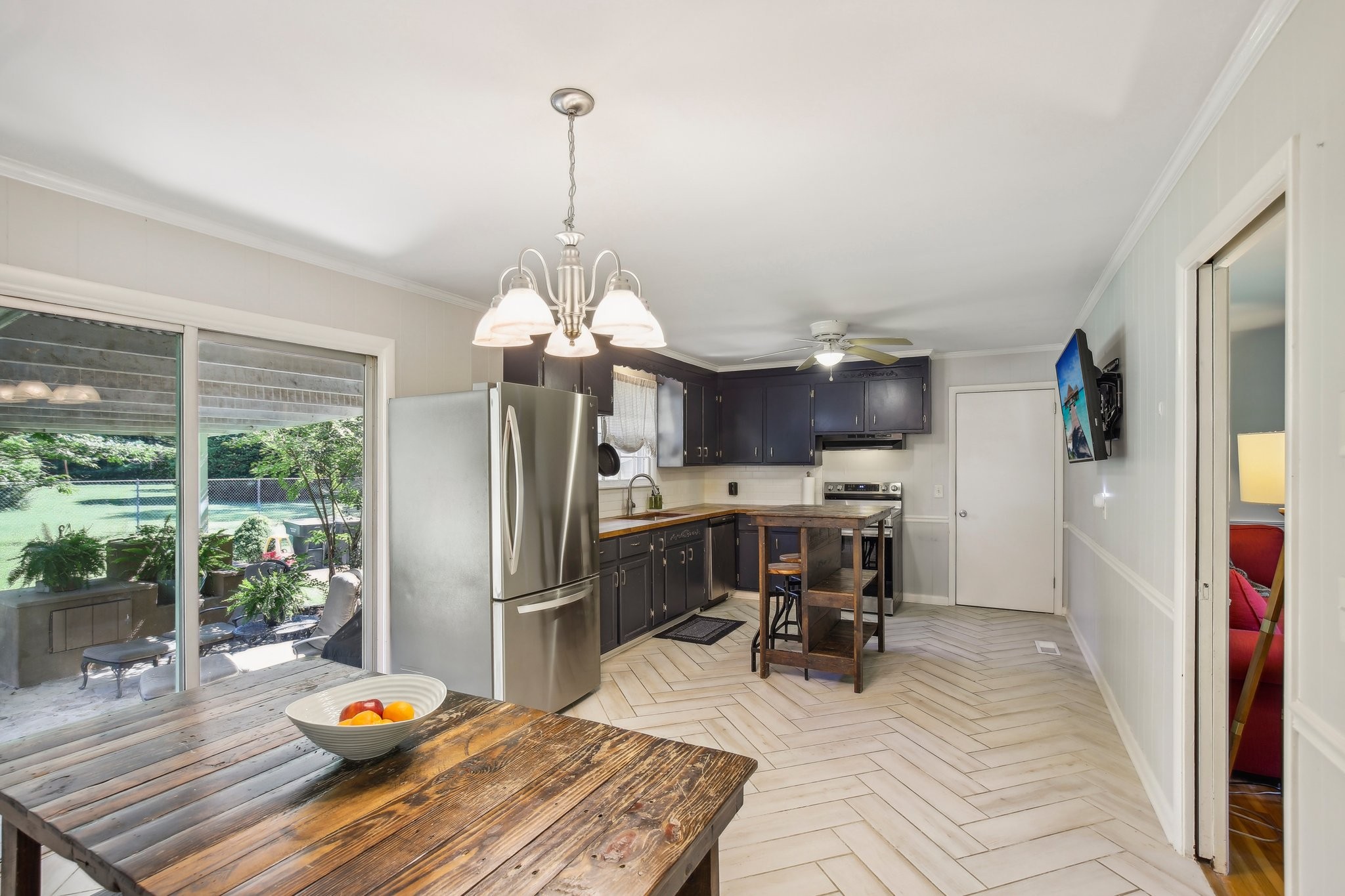 Kitchen with dark cabinets, stainless steel appliances, rustic wooden island, and sliding doors to a garden patio.