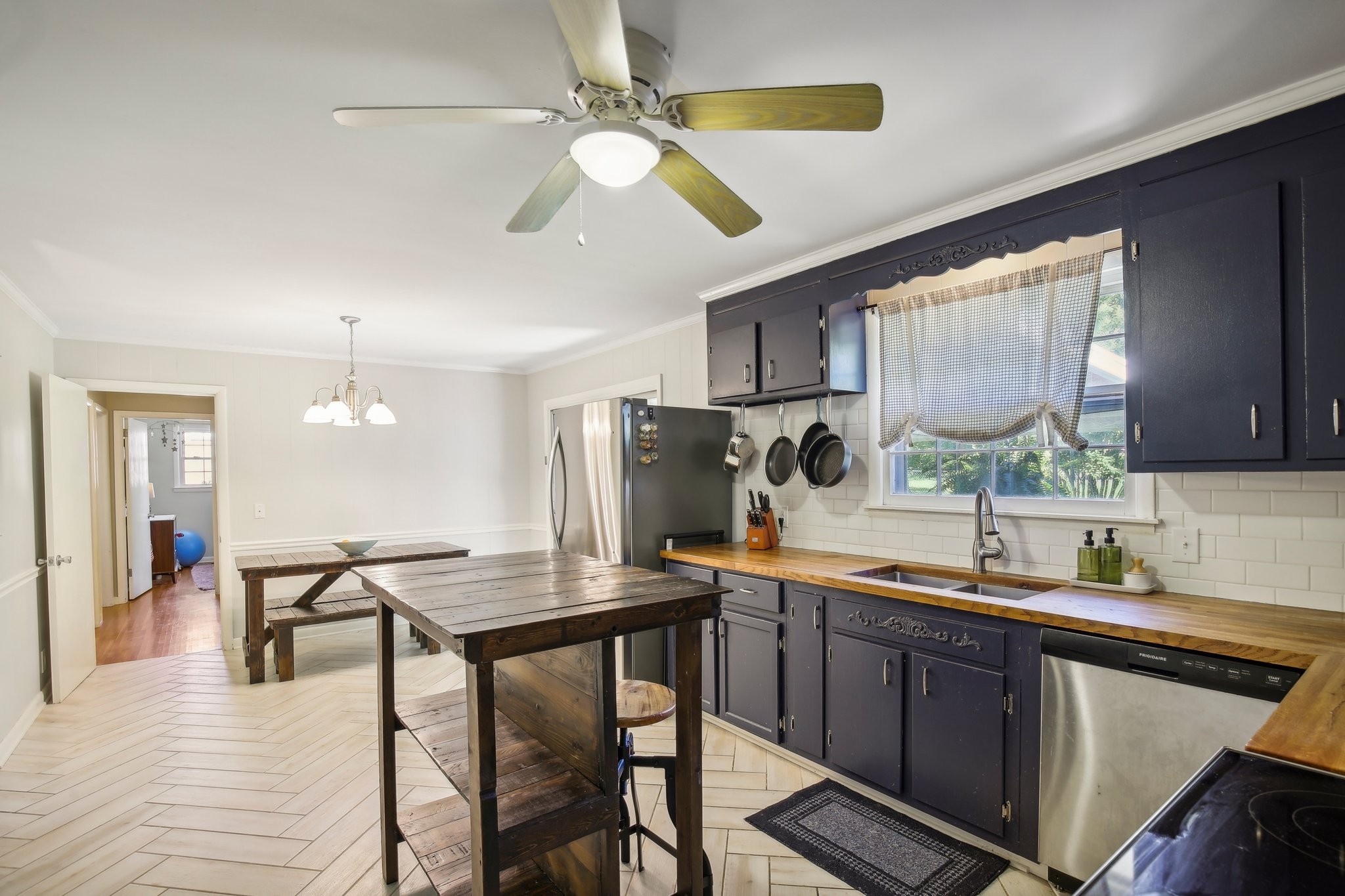 Kitchen with navy cabinets, butcher-block counters, and a rustic wooden island and dining table.