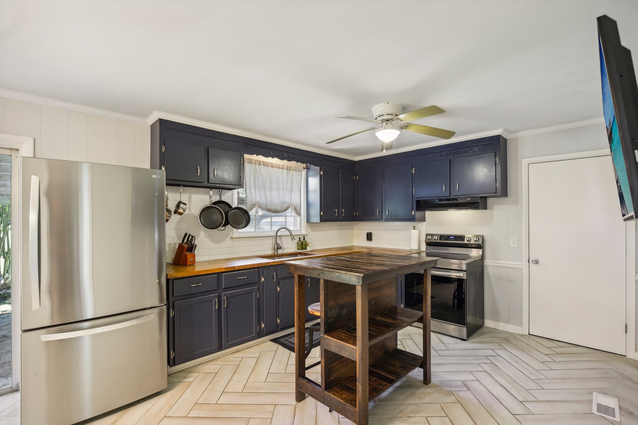 Kitchen with navy cabinets, wood countertops, stainless steel appliances, and a rustic open-shelf island.
