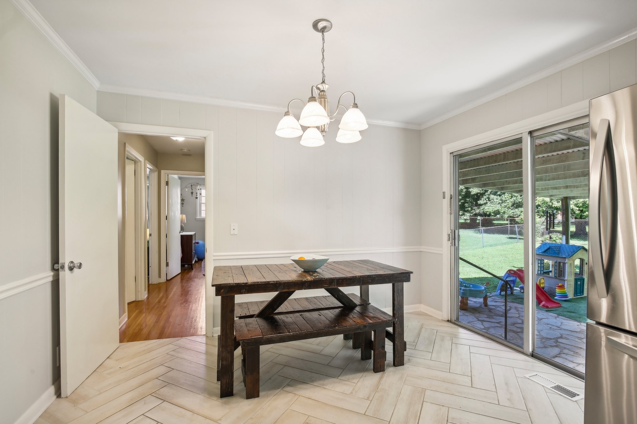 Dining area with a rustic wood table, sliding glass doors, and a view of a backyard playset.