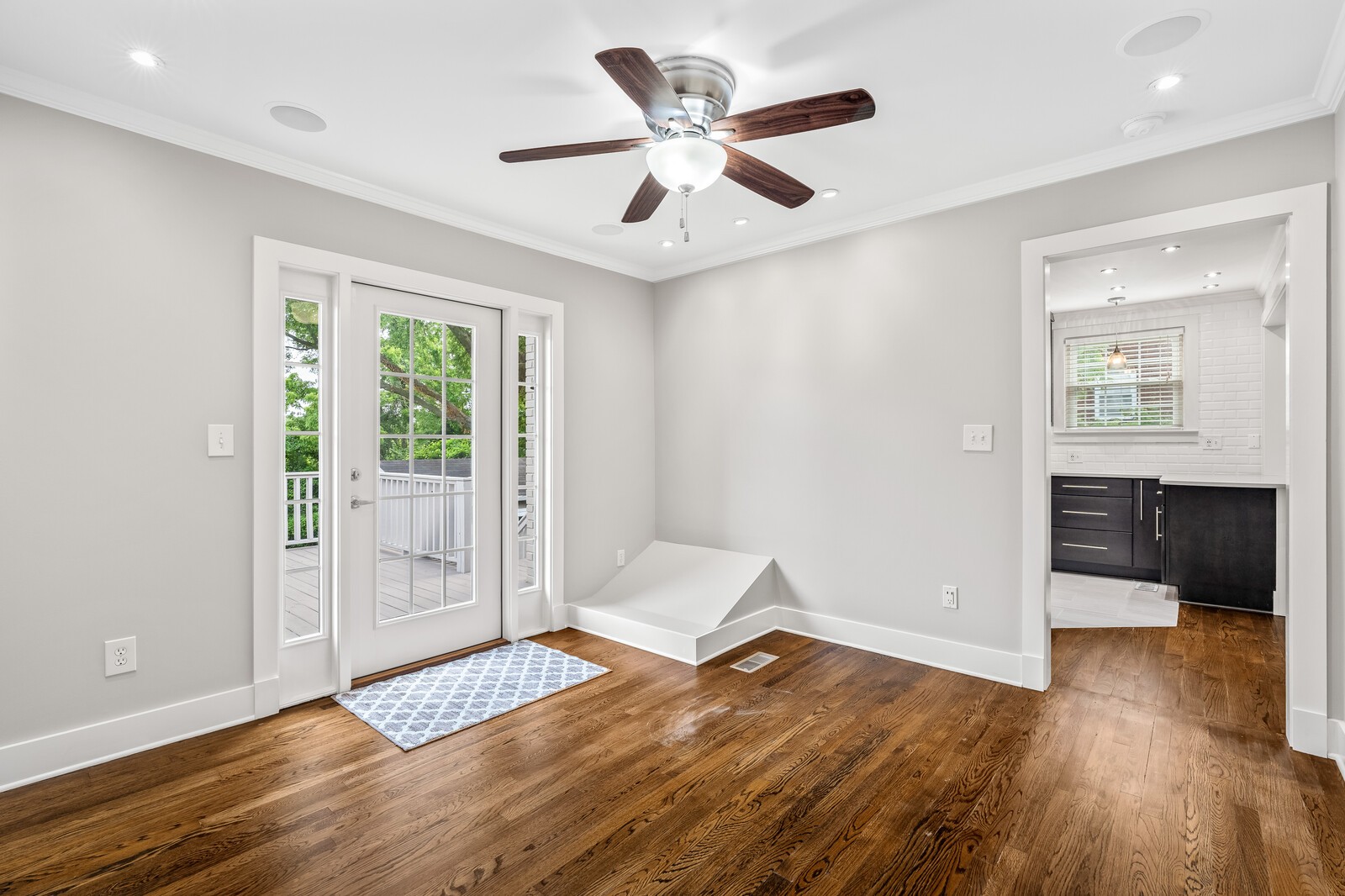 Unfurnished room with hardwood floors, a ceiling fan, and glass doors opening onto a deck.