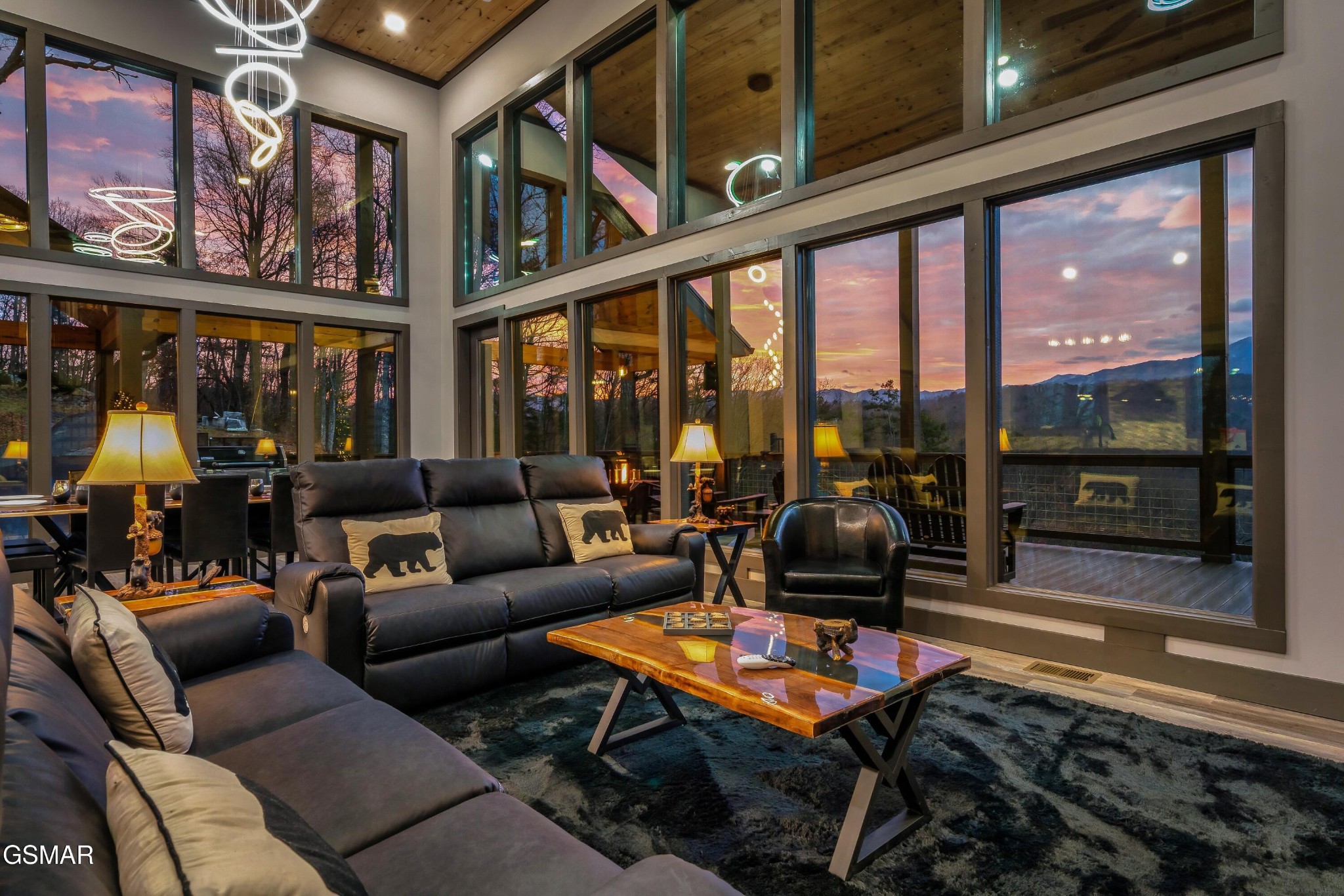 Living room with leather seating and expansive windows overlooking mountains at sunset.