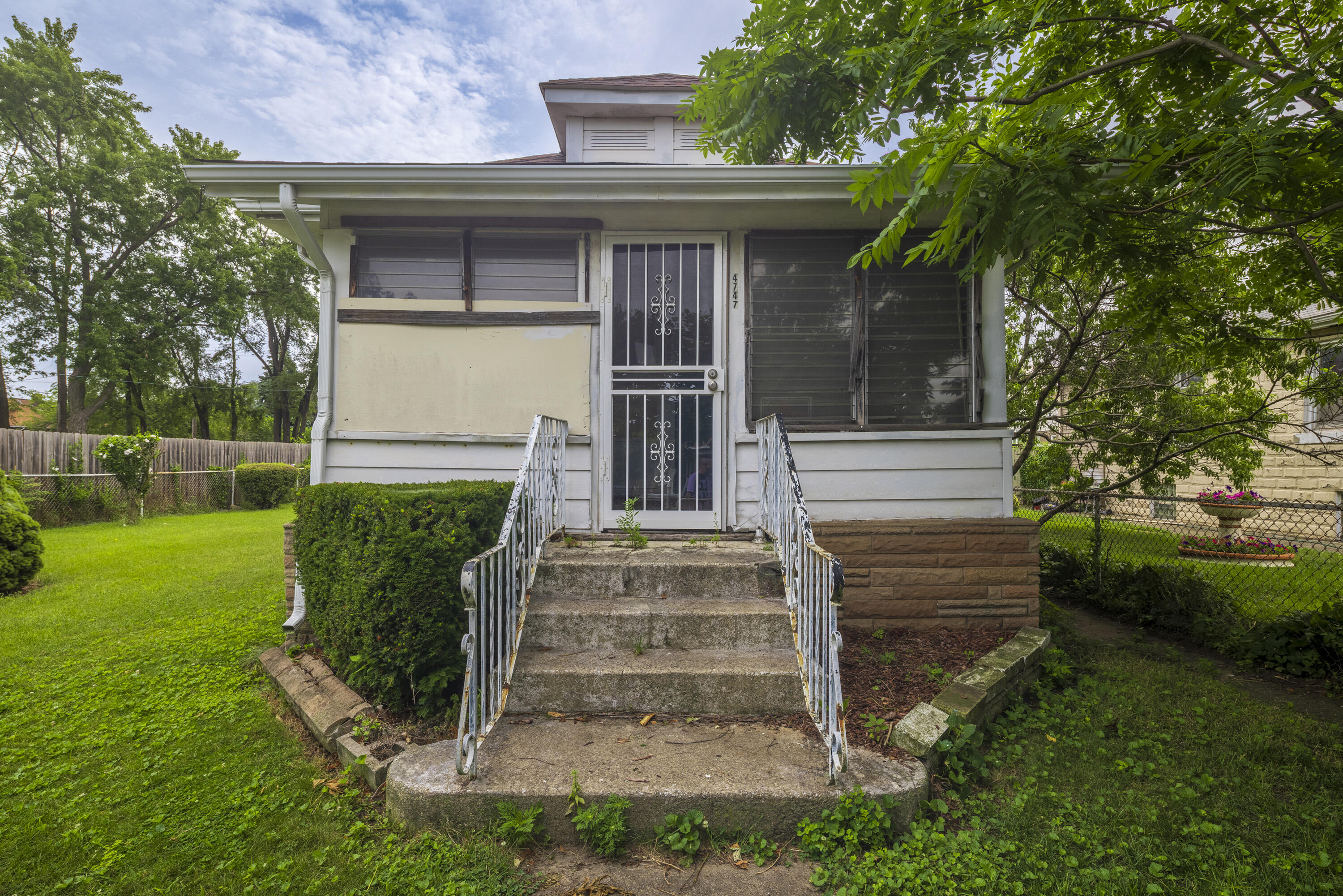 Front of 4747 Drummond Street, with concrete steps, metal railings, and mature trees.