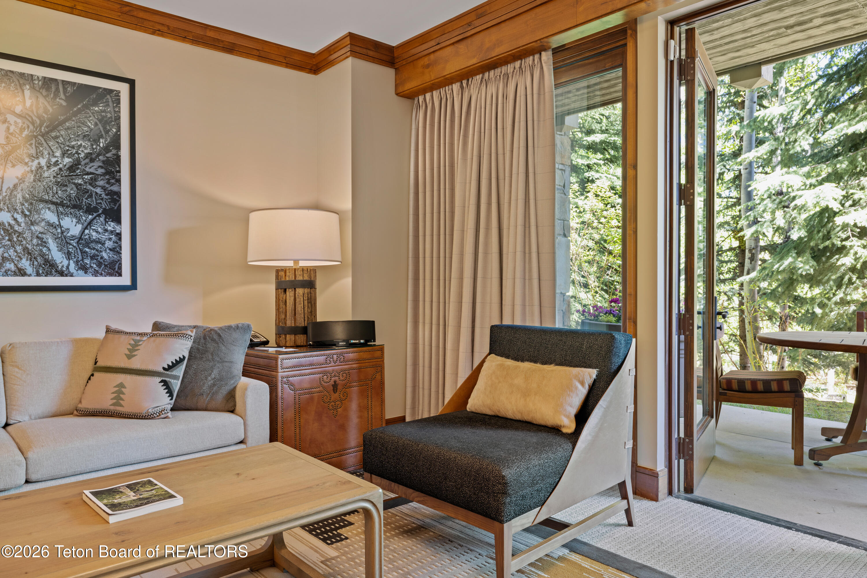 Living room with a light sofa, dark chaise lounge, and open door to a wooded patio.