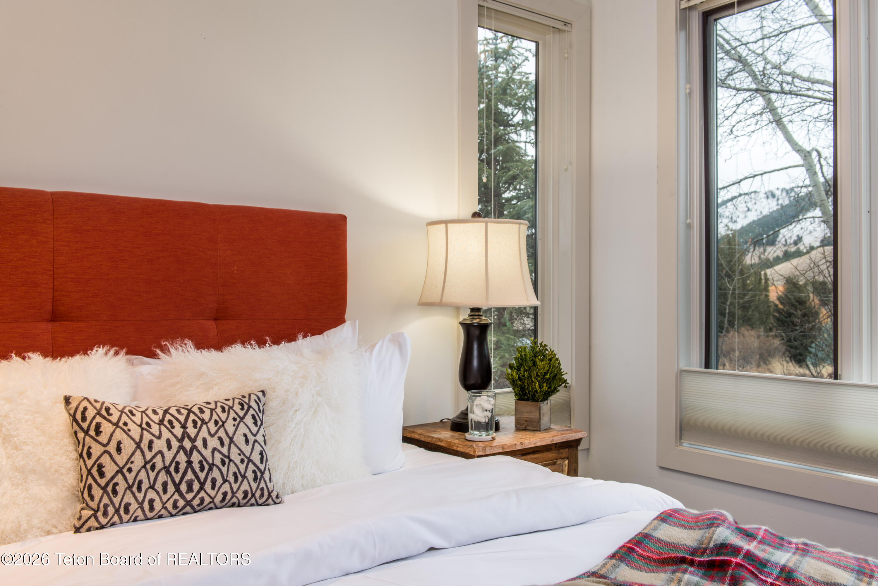 Bedroom with a rust-colored headboard, white bedding, and windows overlooking a snowy hillside.