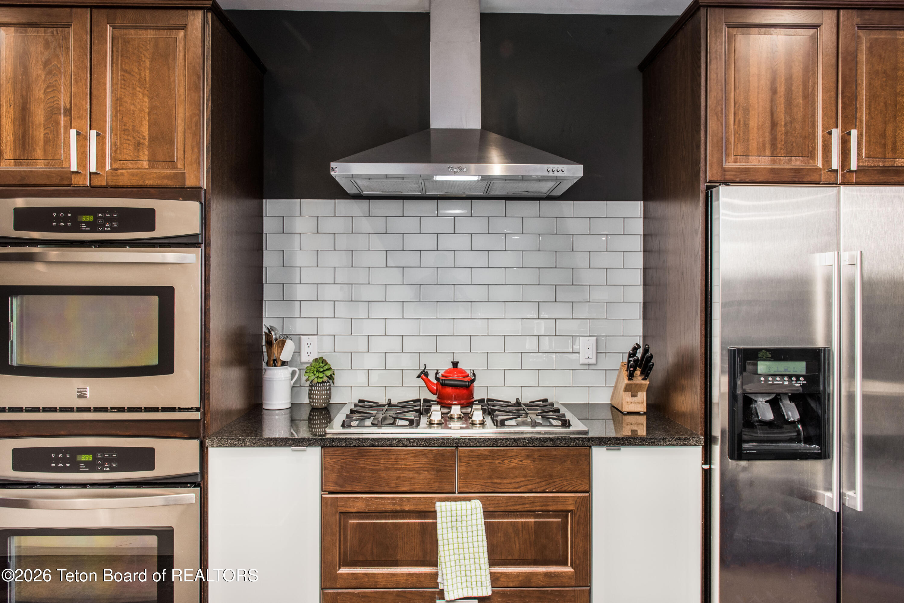 Kitchen with wood cabinets, stainless appliances, and a gas cooktop with a red kettle.