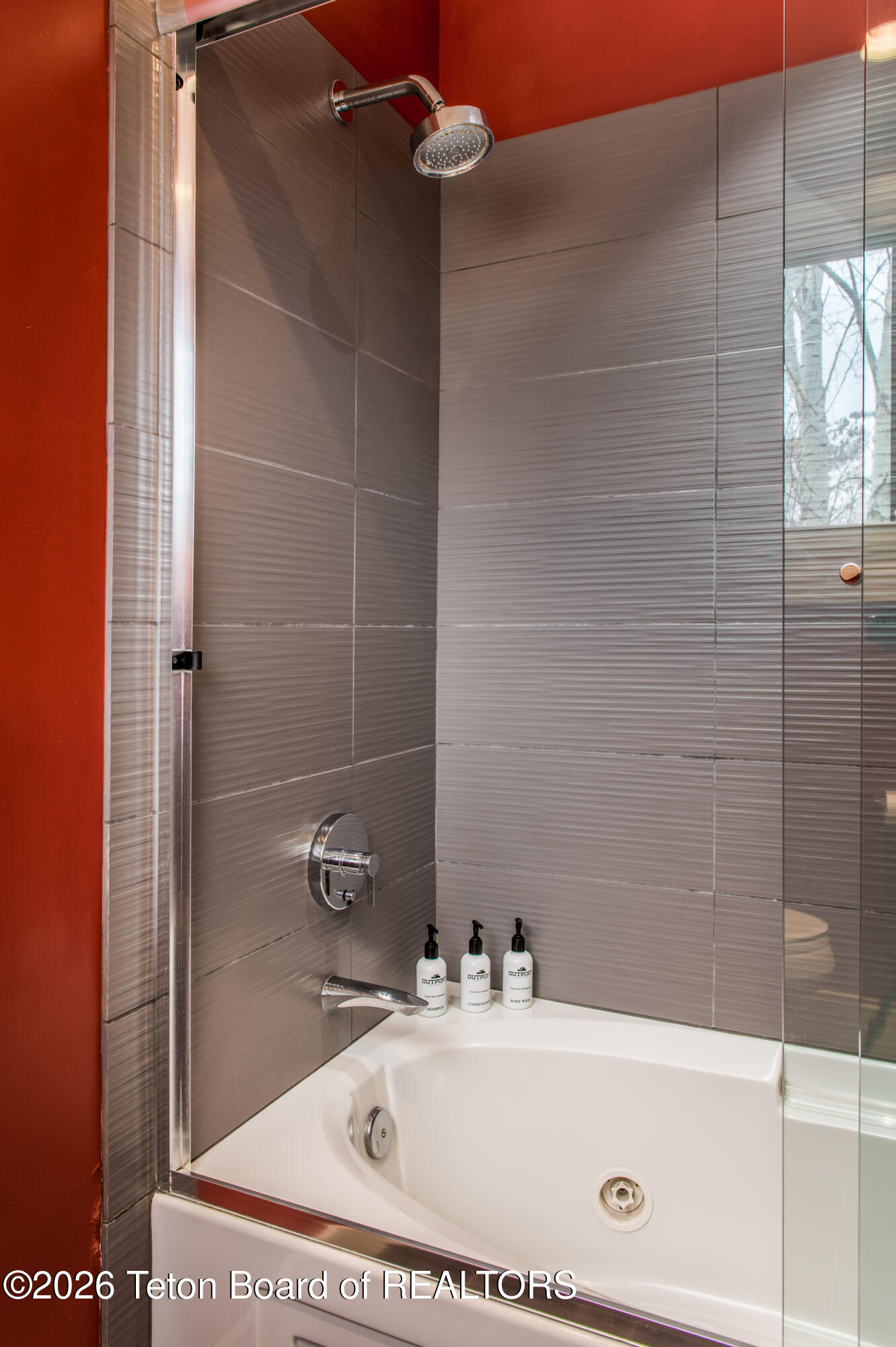 Modern tiled shower and white jetted bathtub with glass enclosure and chrome fixtures.