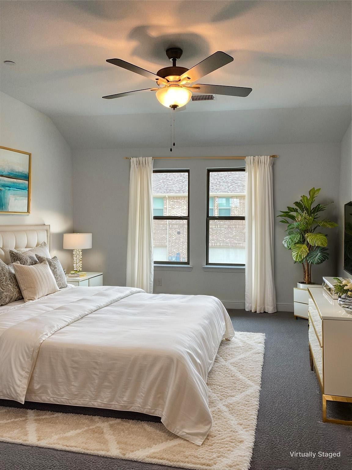 Staged bedroom with a white bed, twin windows, and a ceiling fan.