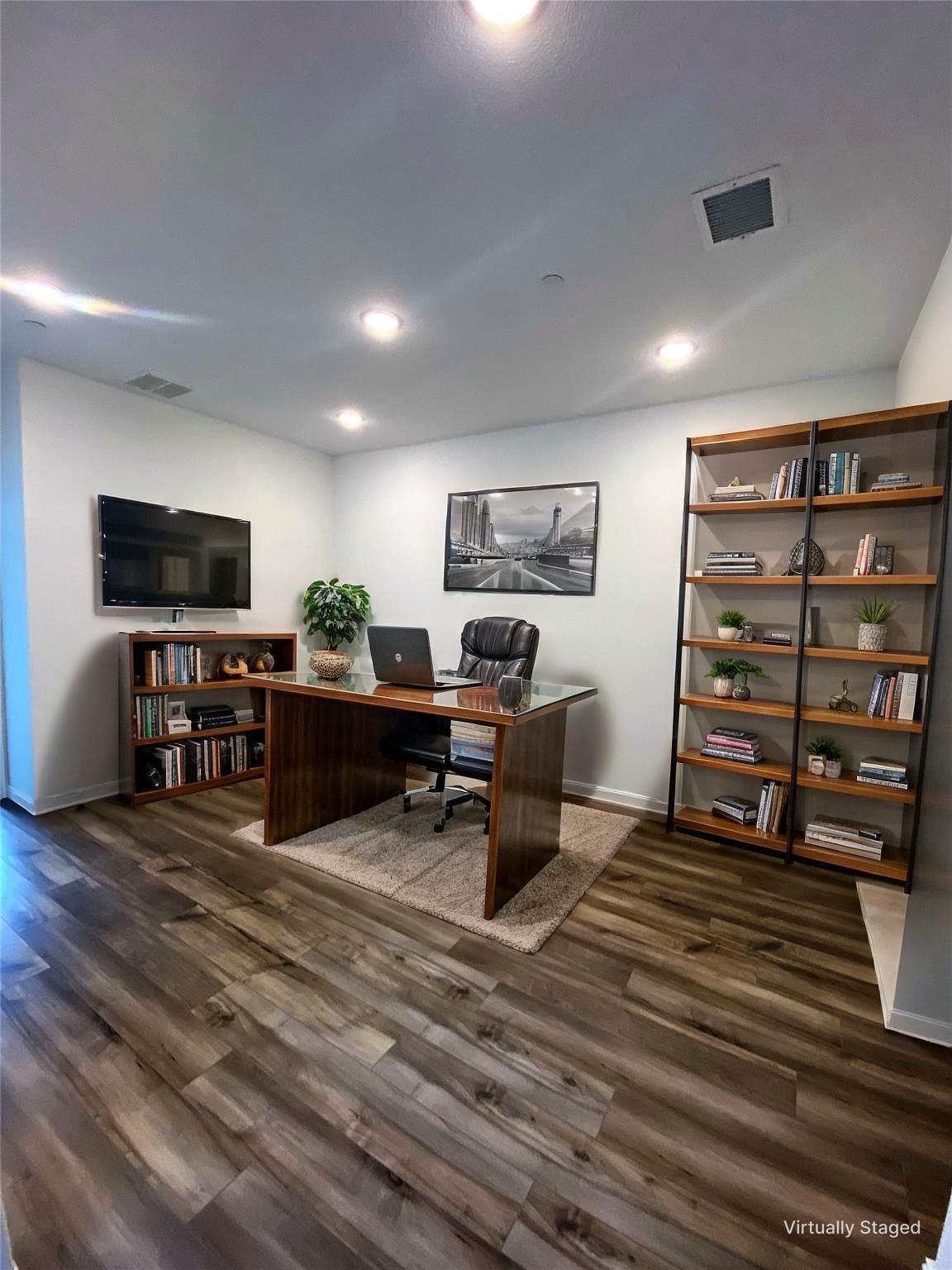 Home office with a glass-top wooden desk, black office chair, and tall bookshelves.