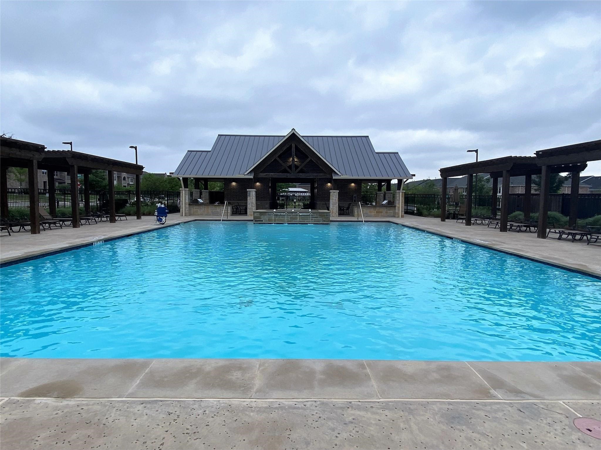Community swimming pool with a covered pavilion and shaded lounge seating.