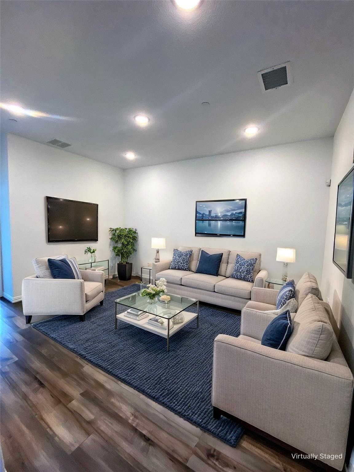 Staged living room with beige seating, a glass coffee table, and a large navy rug.