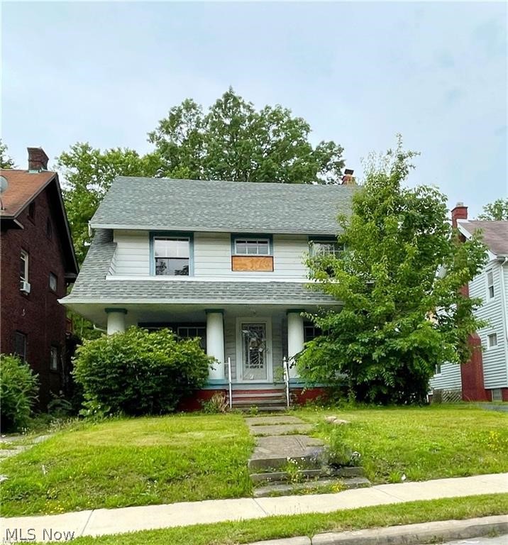 Two-story white house with a covered porch, concrete entry steps, and a plywood-covered upper window.
