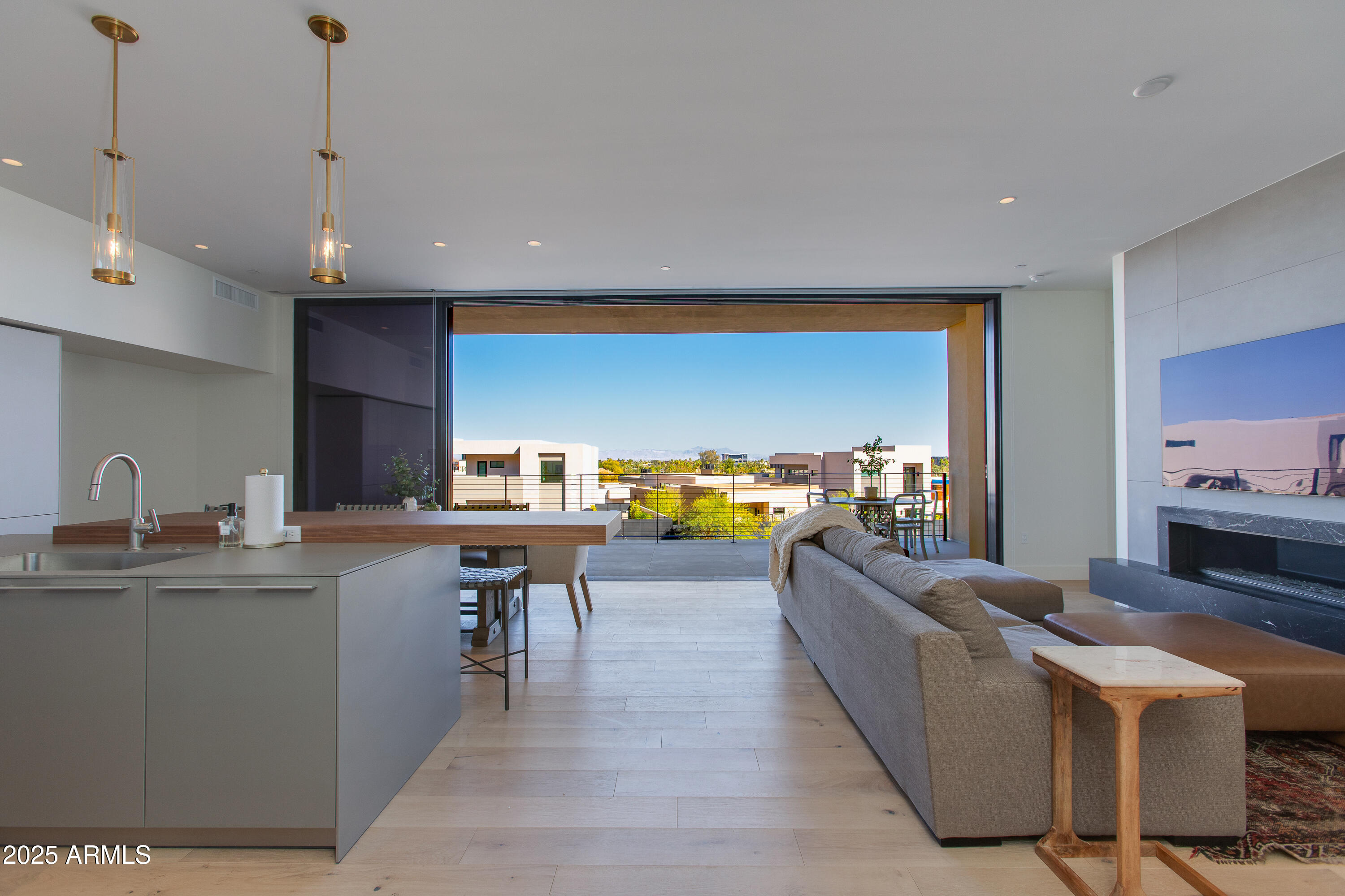 Open-plan living room and kitchen with a modern fireplace and wide terrace views.