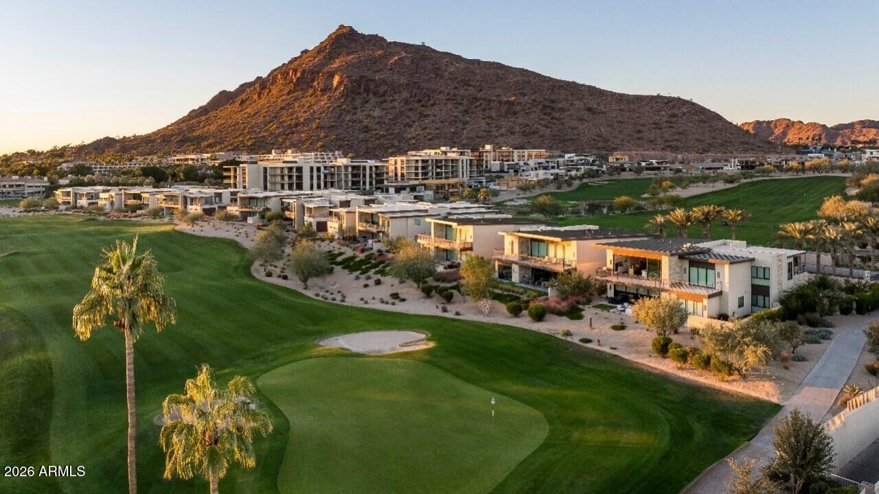 Aerial view of golf course and residences beneath Camelback Mountain at golden hour.
