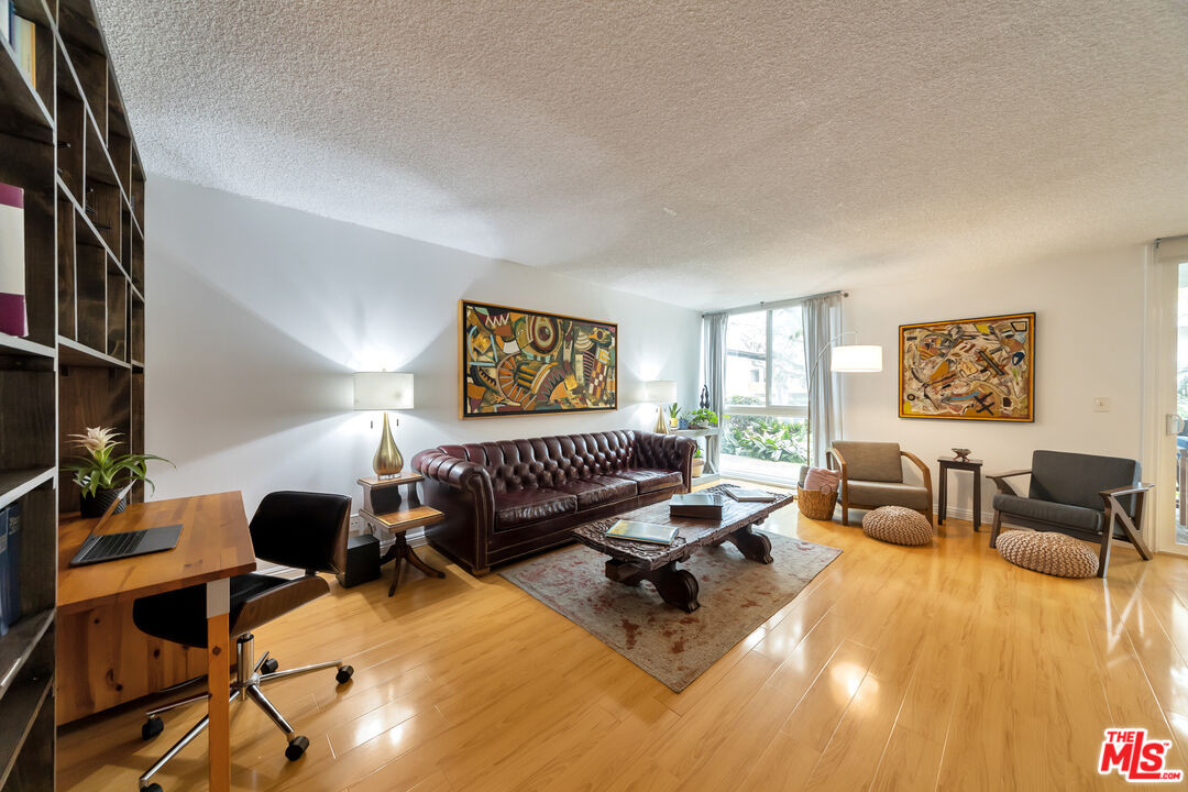 Living room with hardwood floors, leather sofa, built-in shelving, and colorful wall art.