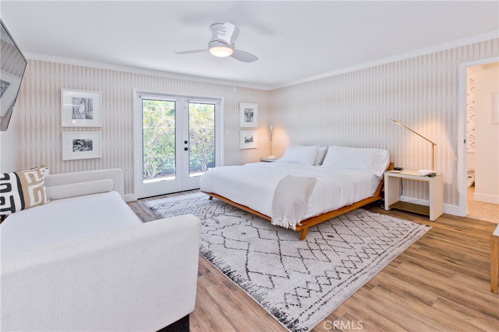 Bedroom with a white bed, sofa, patterned rug, and French doors.