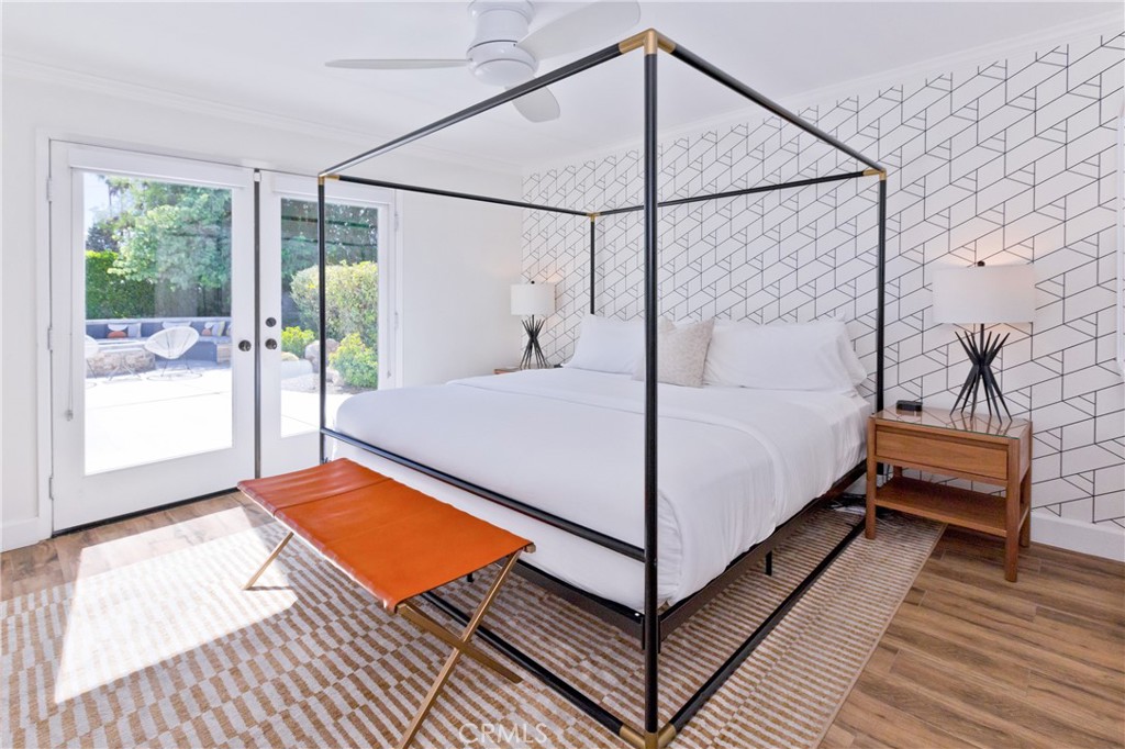 Bedroom with a black canopy bed, geometric accent wall, and glass doors opening to a garden patio.