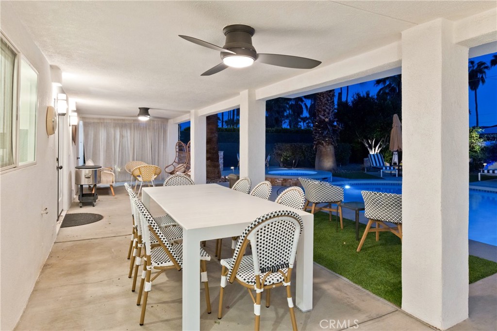 Covered patio dining area beside an illuminated swimming pool at night.