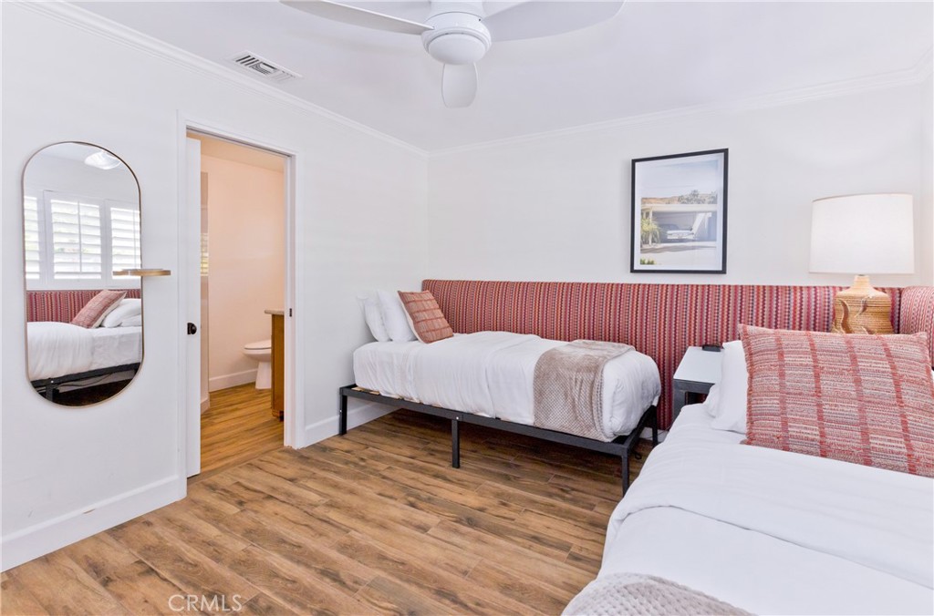 Bedroom with two beds, patterned headboards, white bedding, and wood-look flooring.