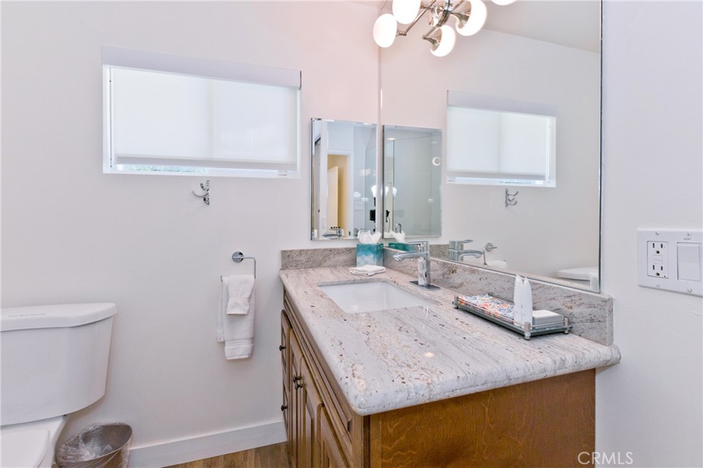 Bathroom vanity with a pale stone countertop, undermount sink, and large mirror.