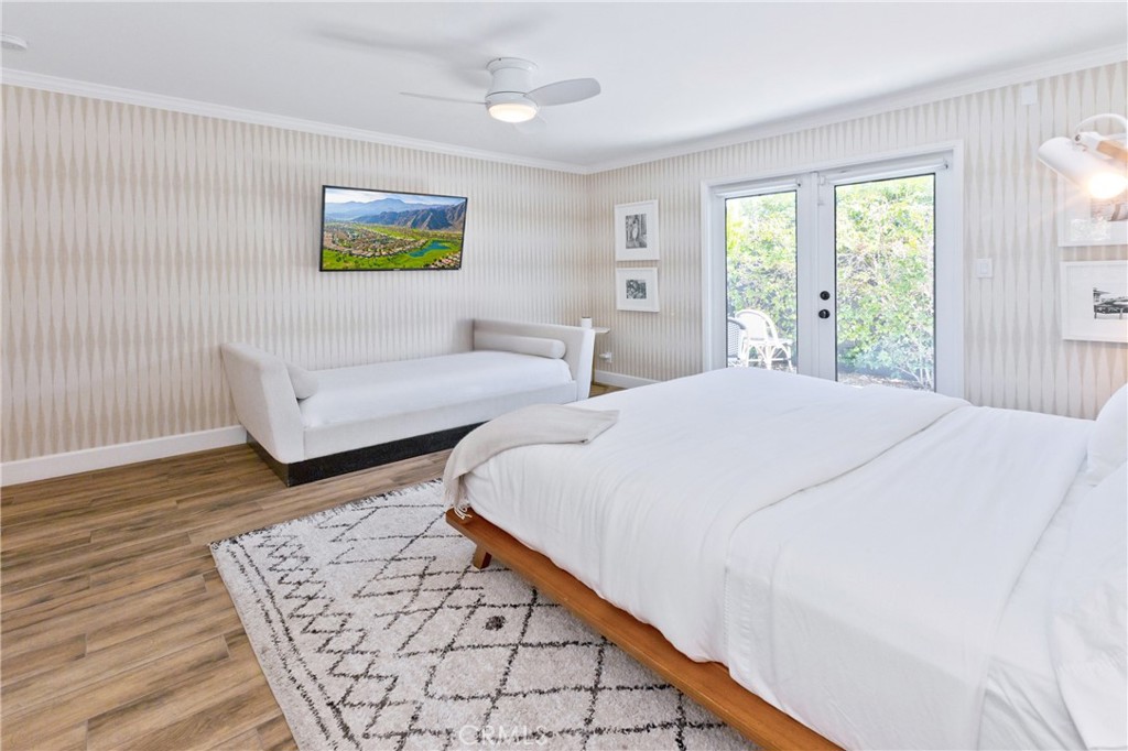 Bright bedroom with a large white bed, daybed, and glass doors opening to greenery.