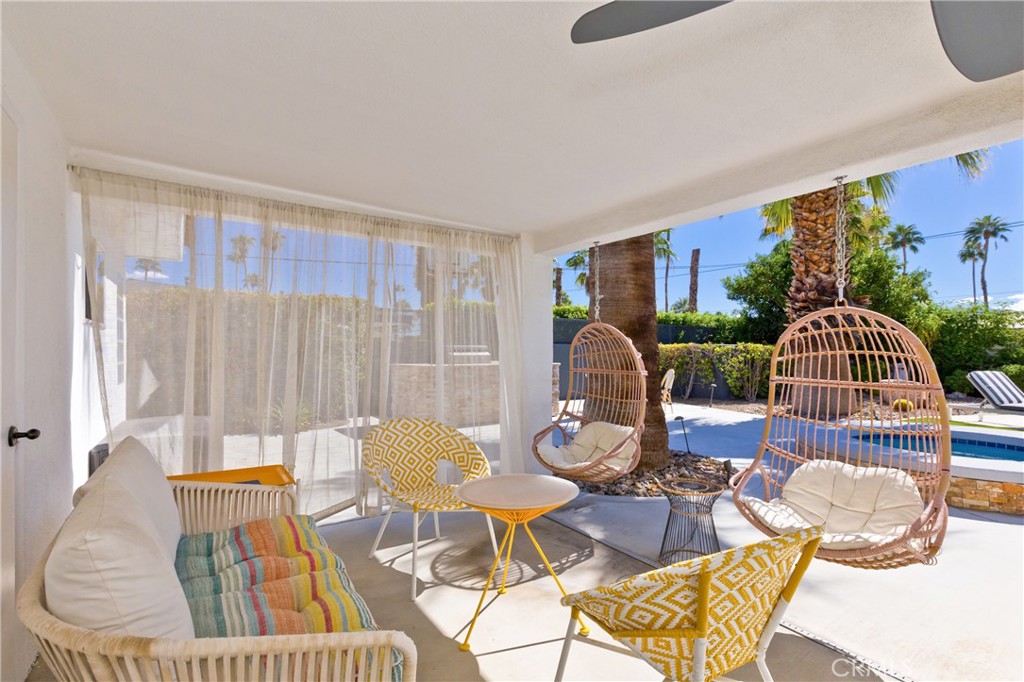 Covered patio with woven lounge chairs overlooking a palm-lined backyard pool.